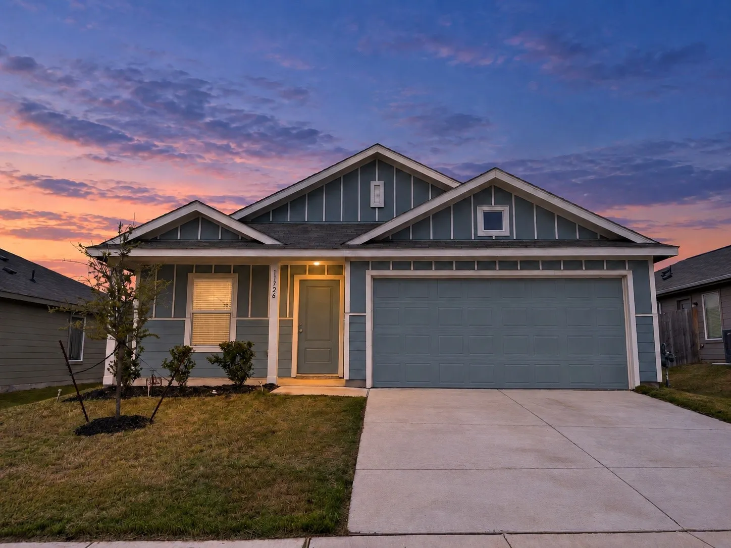 *Digitally Enhanced* Front exterior at twilight showcasing the home’s inviting covered entry, distinctive blue-and-white exterior, and attached two-car garage.