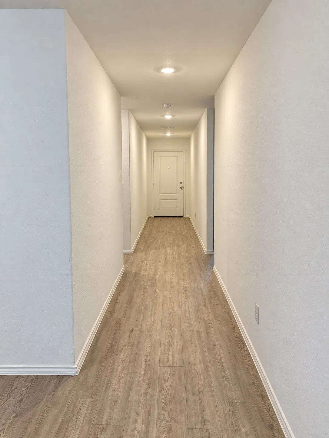 Bright, welcoming entry hallway featuring luxury vinyl plank flooring, recessed lighting, and neutral finishes that create a clean, cohesive look