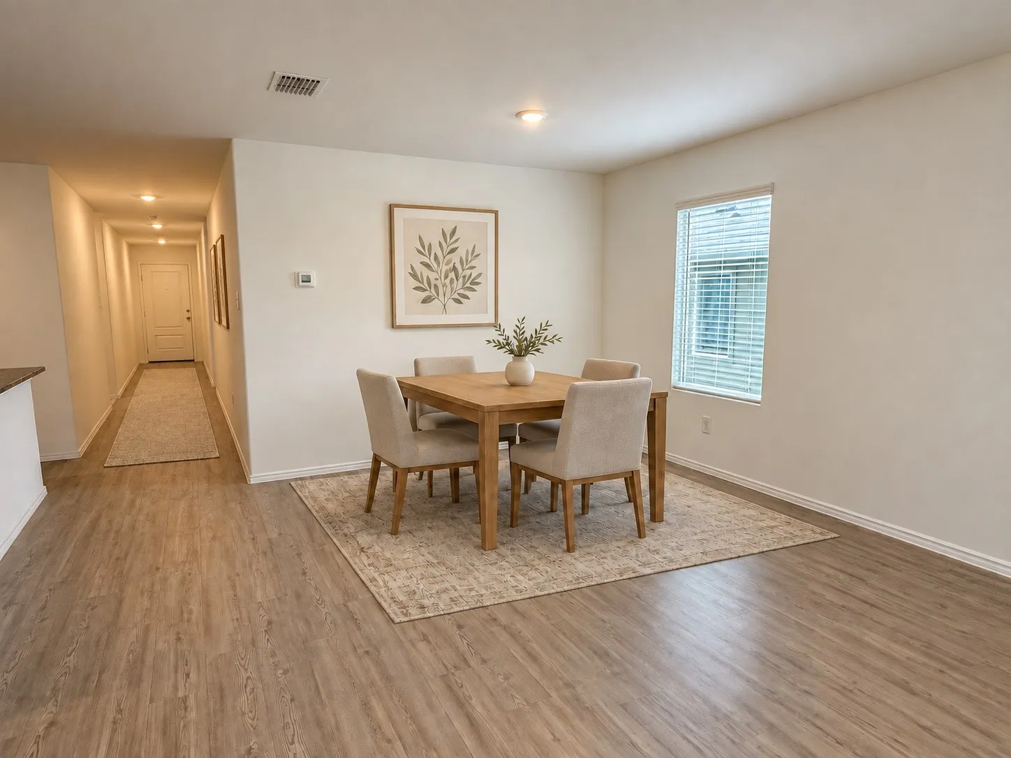 *Virtually Staged* Open dining area with luxury vinyl plank flooring, recessed lighting, and a large window providing natural light, with easy flow to the kitchen and living space.