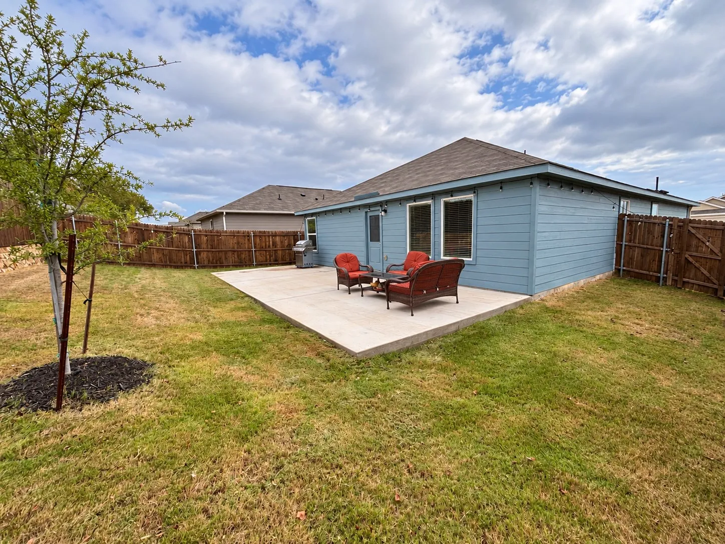 Spacious fenced backyard with an extended concrete patio offering plenty of room for outdoor seating, grilling, and entertaining.