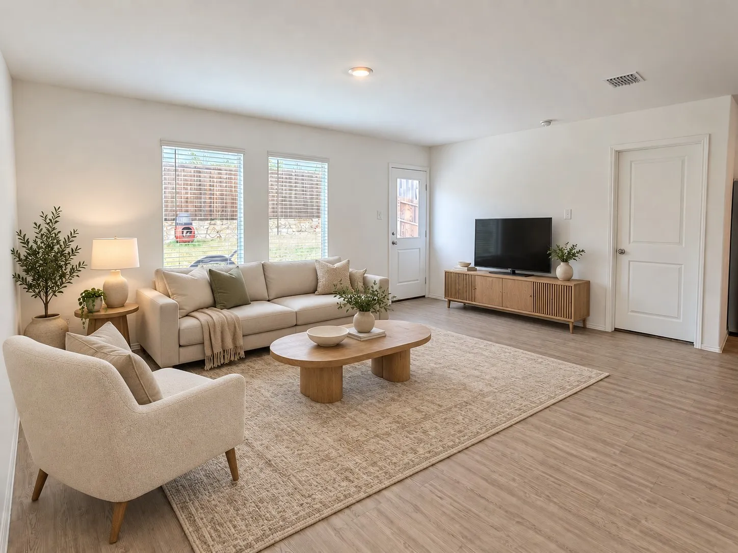 *Virtually Staged* Spacious living area featuring luxury vinyl plank flooring, recessed lighting, abundant natural light, and direct access to the backyard.