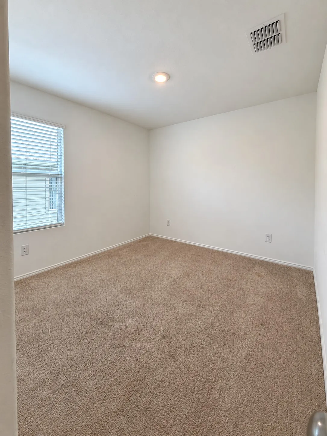 Comfortable secondary bedroom featuring neutral carpeting, recessed lighting, and a window for natural light.