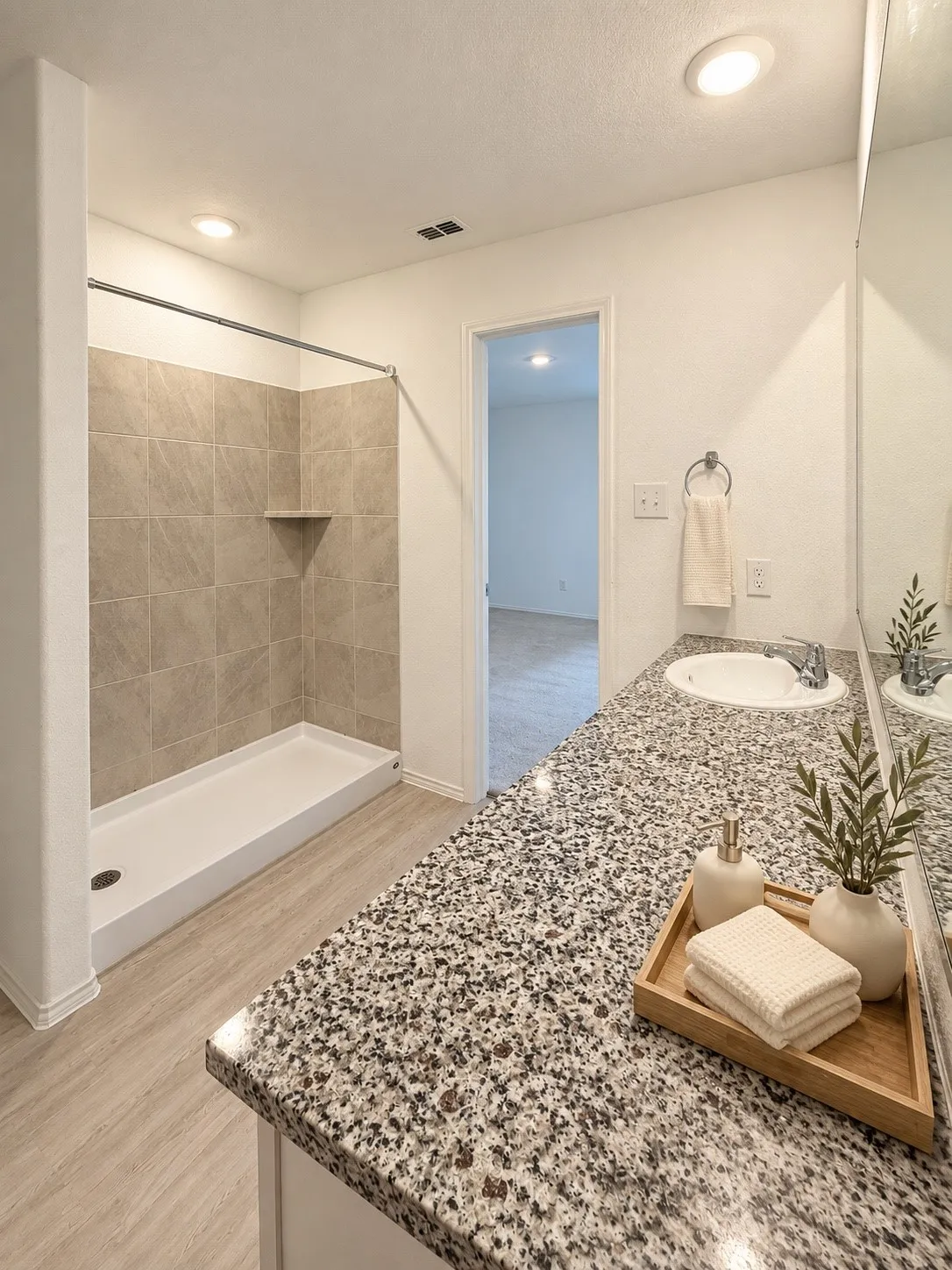 En-suite primary bath featuring a granite countertop vanity, tiled tub and shower surround, recessed lighting, and luxury vinyl plank flooring.