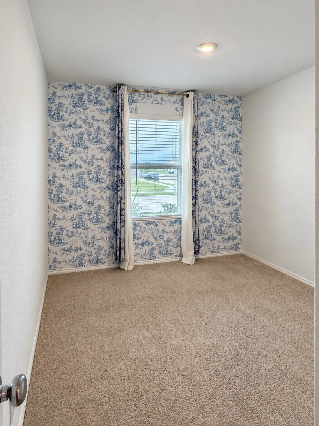 Versatile secondary bedroom featuring neutral carpeting, recessed lighting, a large window for natural light, and an accent wall that adds character to the space.