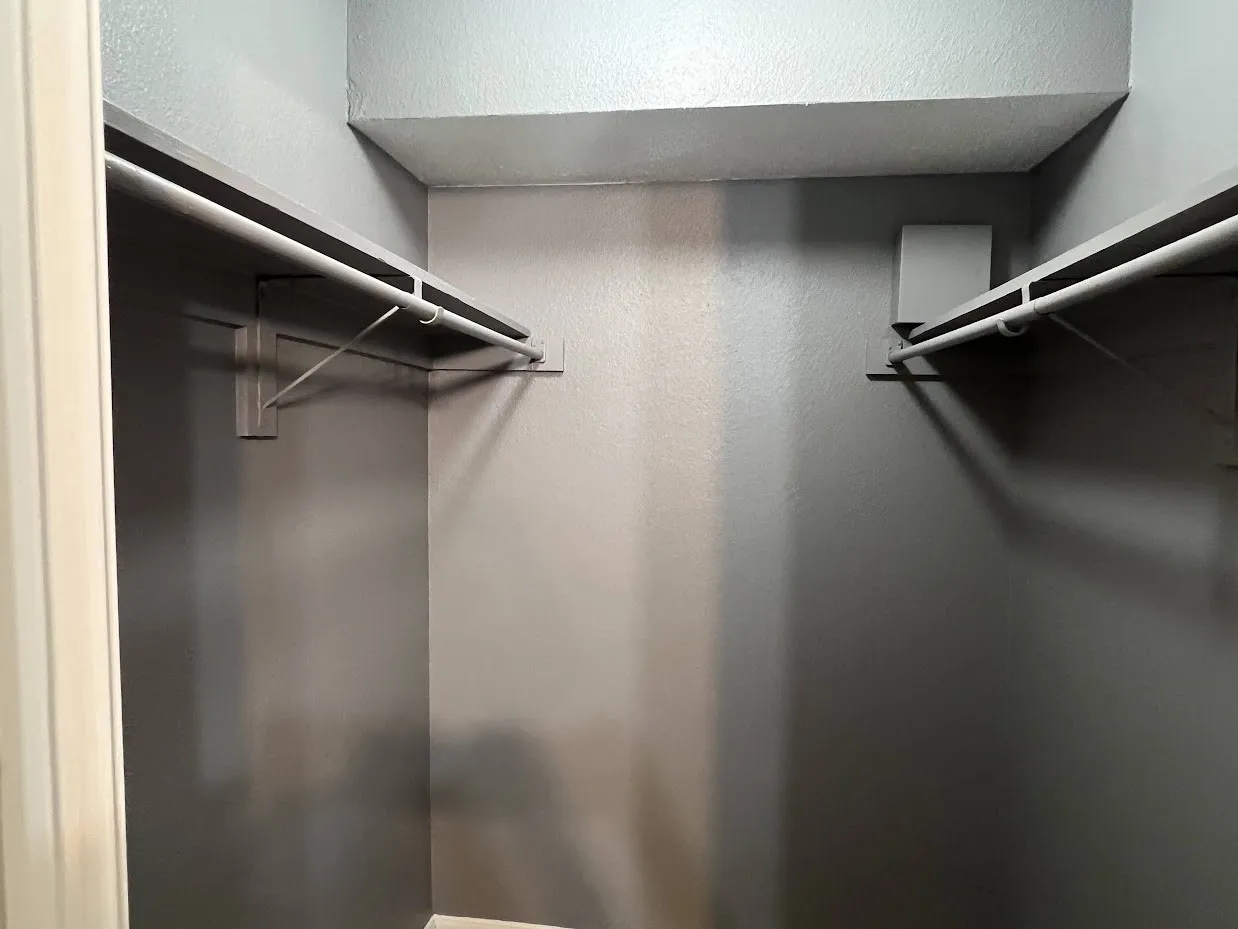 Alcove closet featuring two built-in shelves and two clothing rods