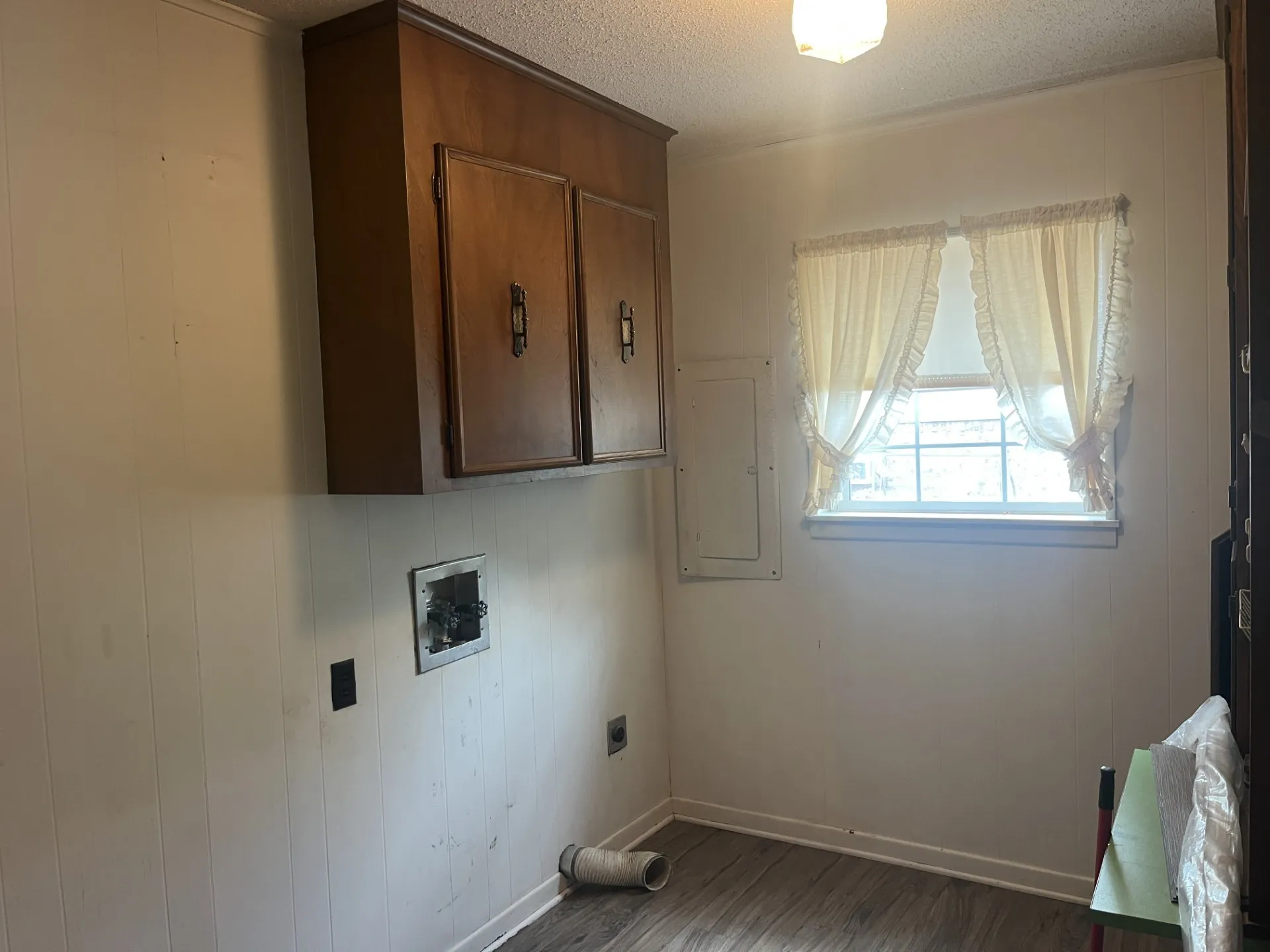Built-in wall cabinetry, panel-style wall finish, window with natural light, and wood-finish flooring
