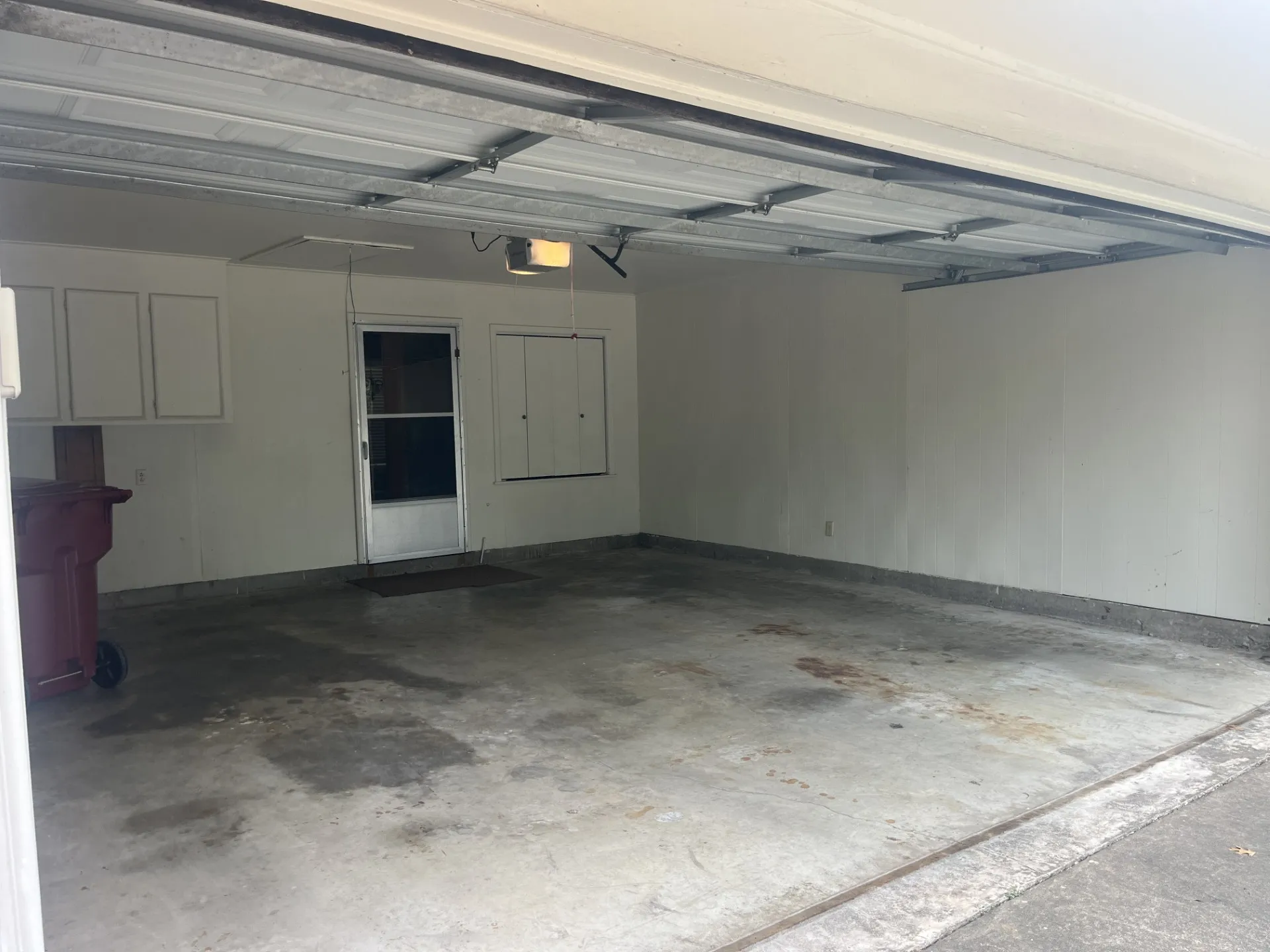 Attached garage featuring a concrete floor, built-in cabinetry, and a service door