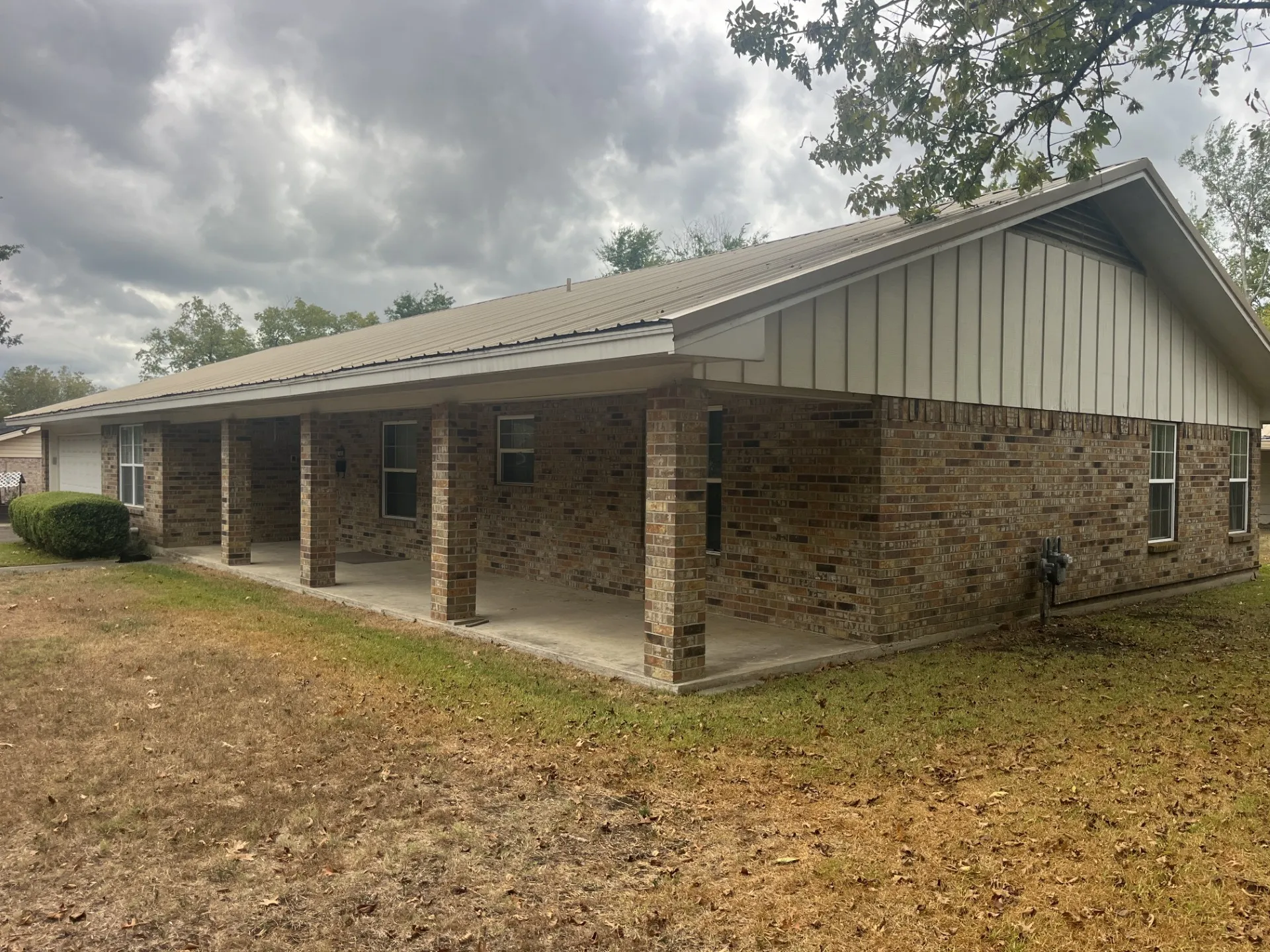Brick exterior with board and batten siding, metal roof, and a covered front porch featuring brick columns