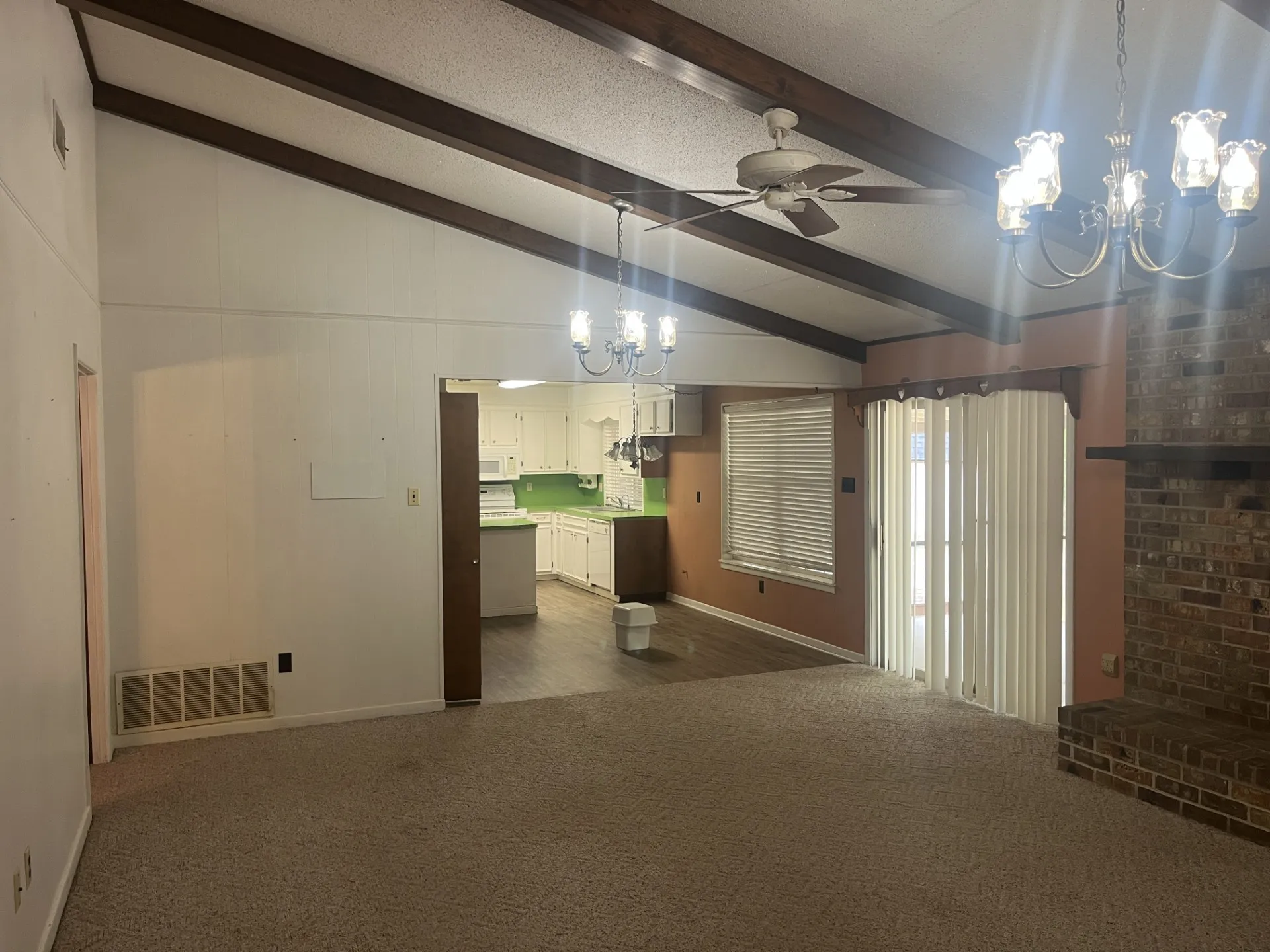 Open living area with exposed beam ceiling detail, ceiling fan, and pendant lighting