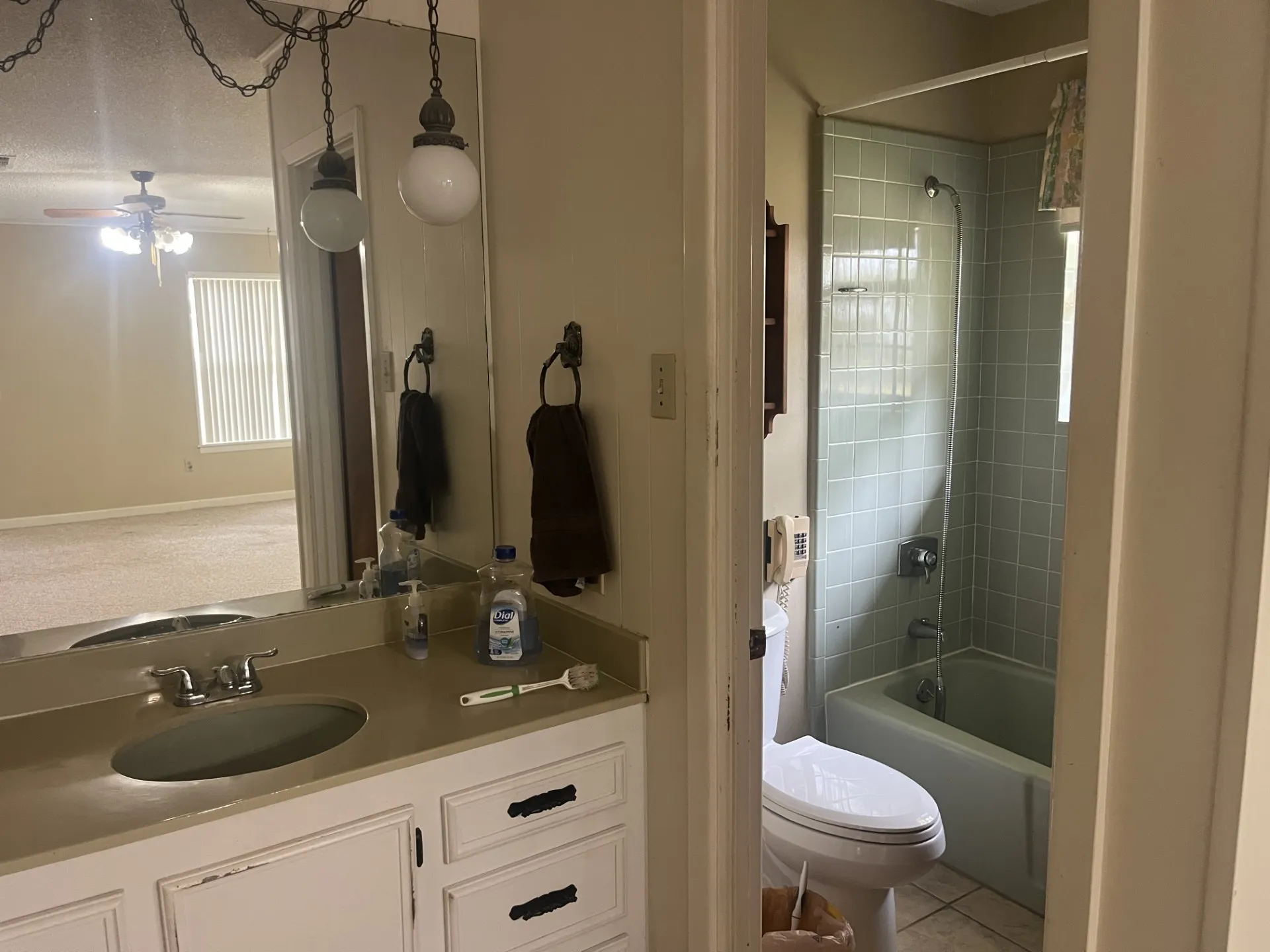 Vanity with an integrated sink, dual hanging light fixtures, and a shower-over-tub combination with tiled walls