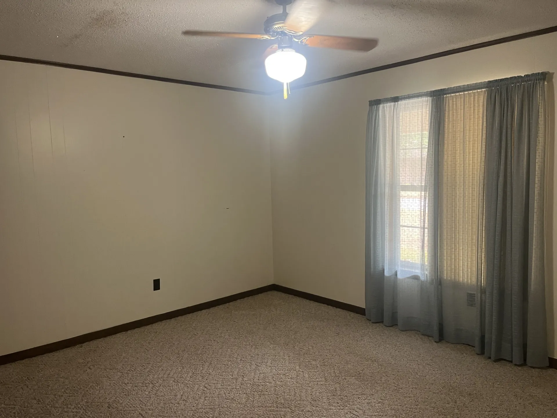 Ceiling fan with integrated lighting, window with drapes, wall-to-wall carpeting