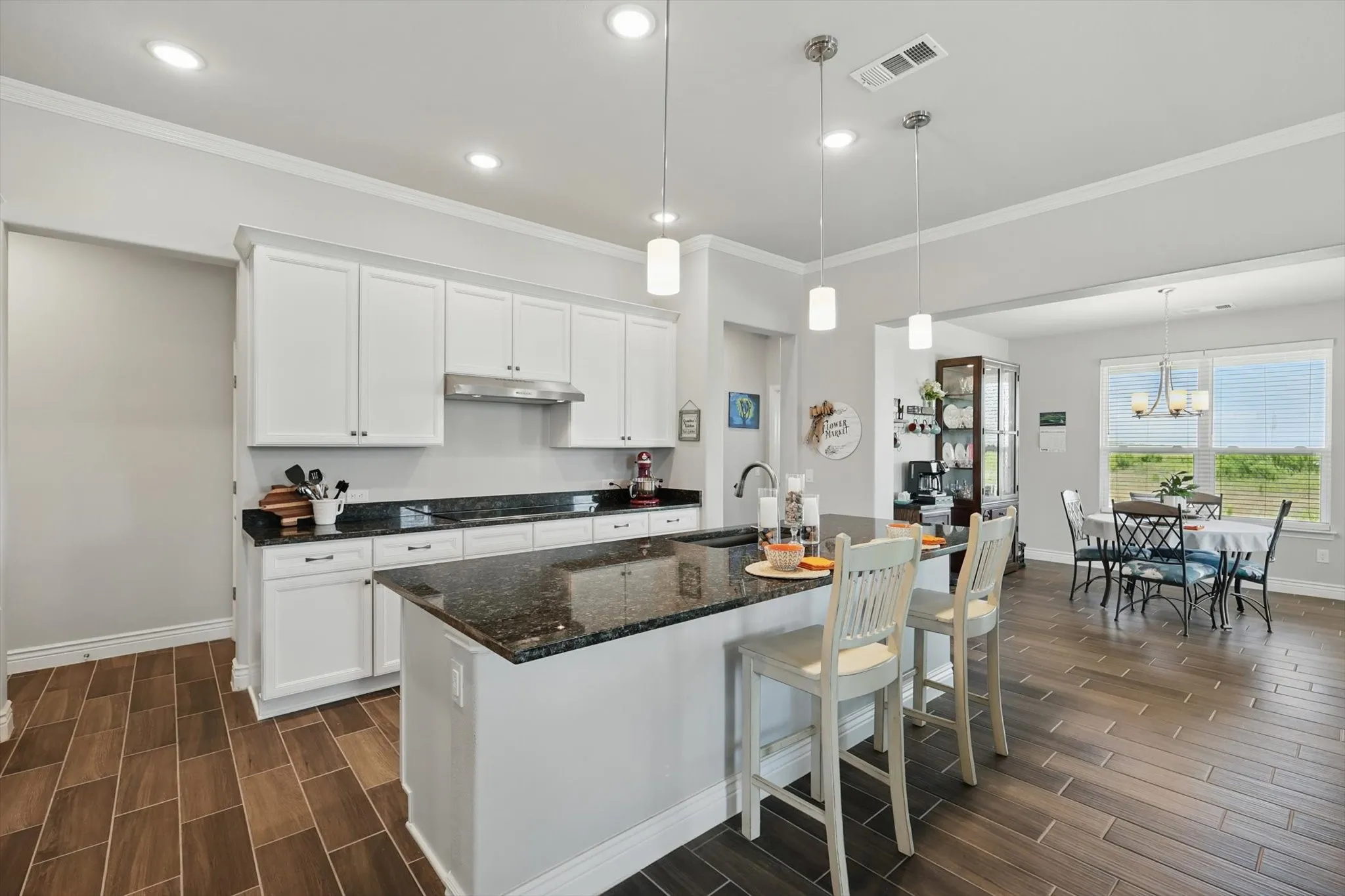 Eat in kitchen with bar, under cabinet  range hood, and black electric cook top.