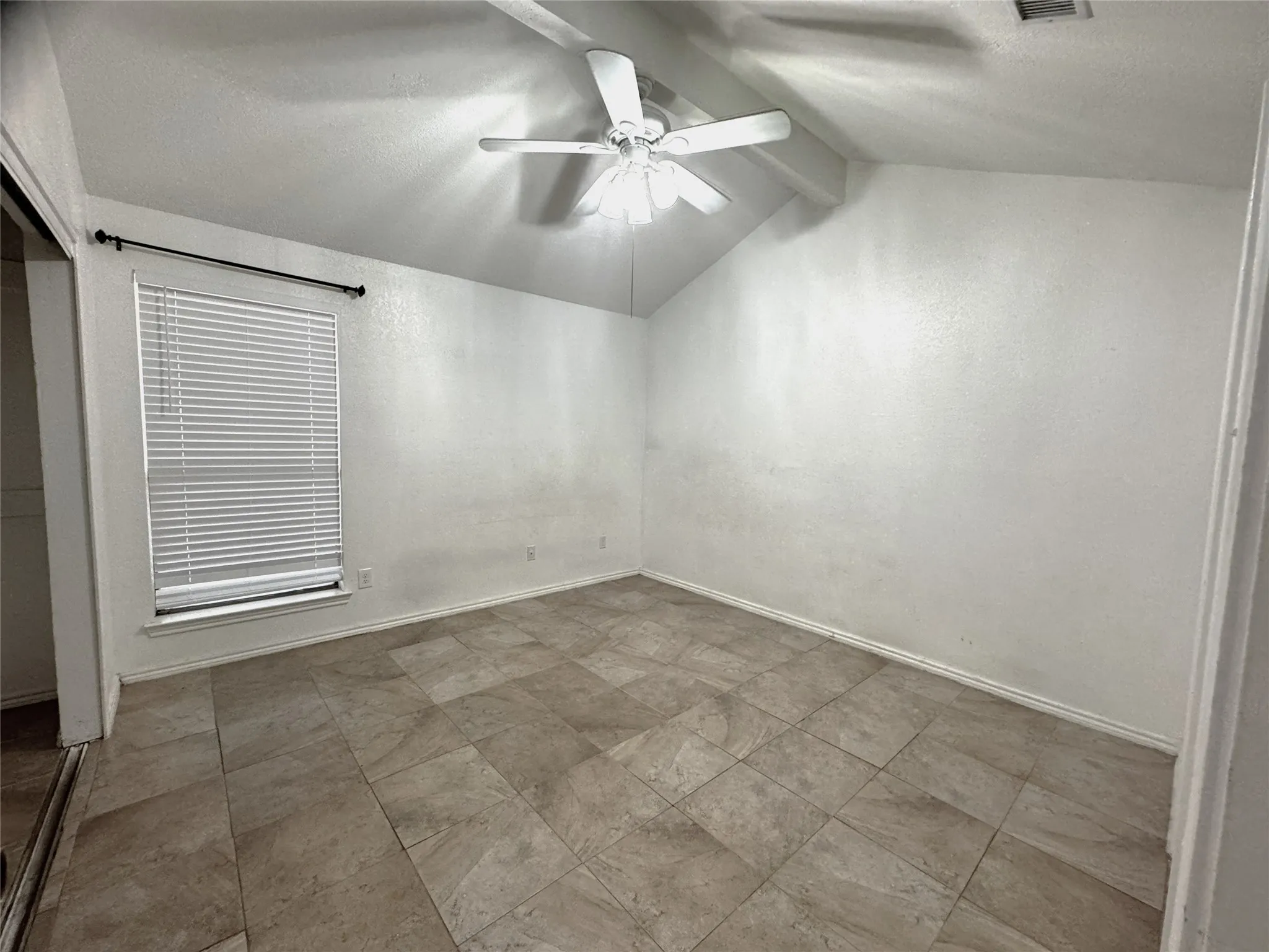 Vaulted ceiling featuring a ceiling fan with integrated lighting, tile flooring, and a window with blinds