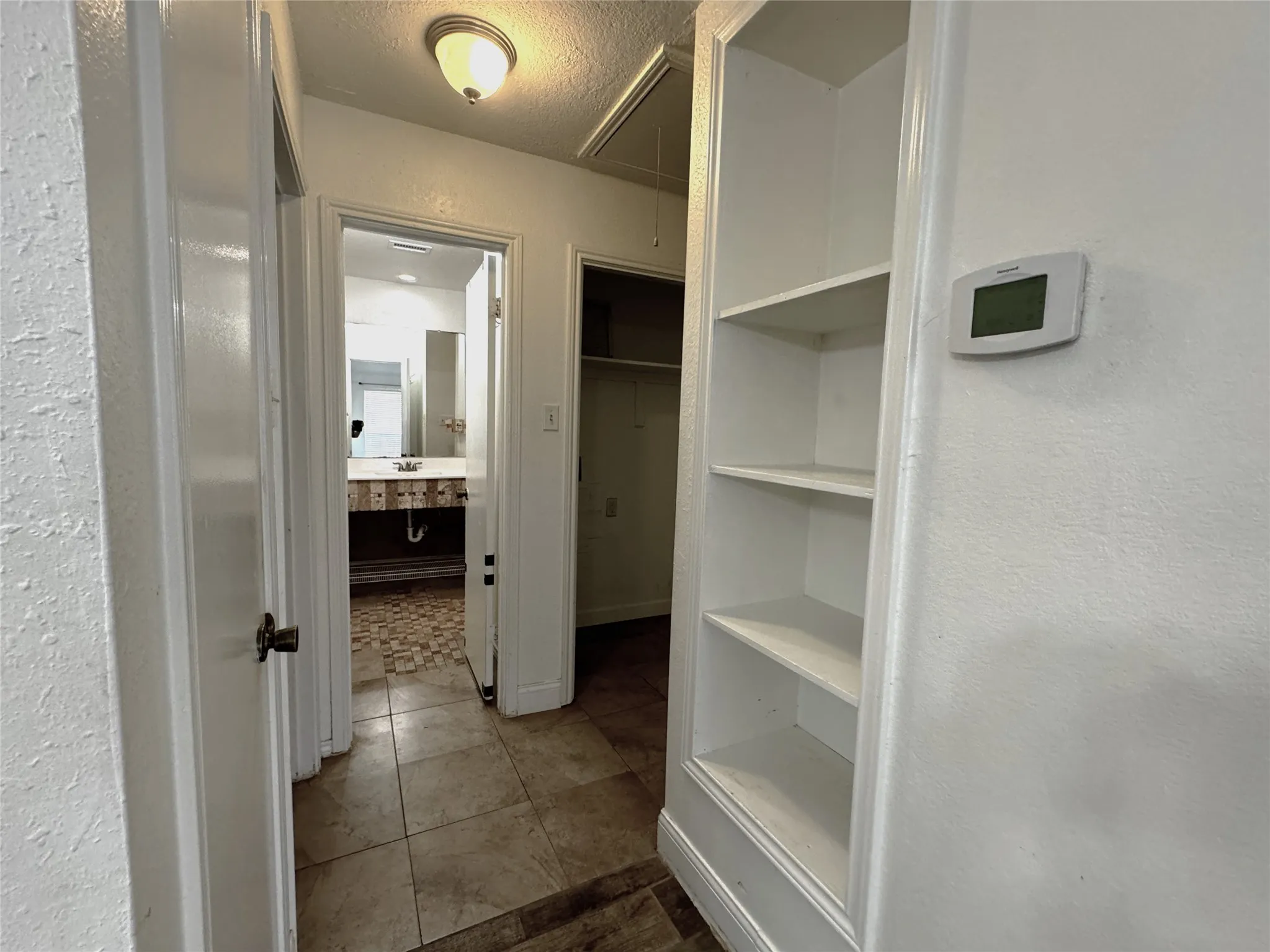 Built-in shelving, corridor with ceiling-mounted light fixture, tile flooring