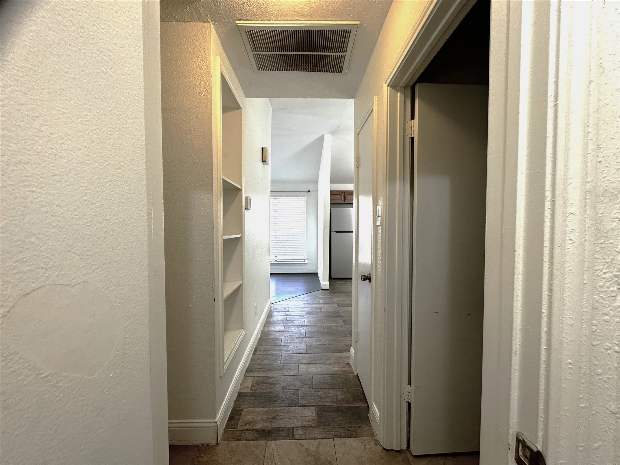 Hallway featuring integrated built-in shelving, wood-finish flooring, and a ceiling-mounted light fixture