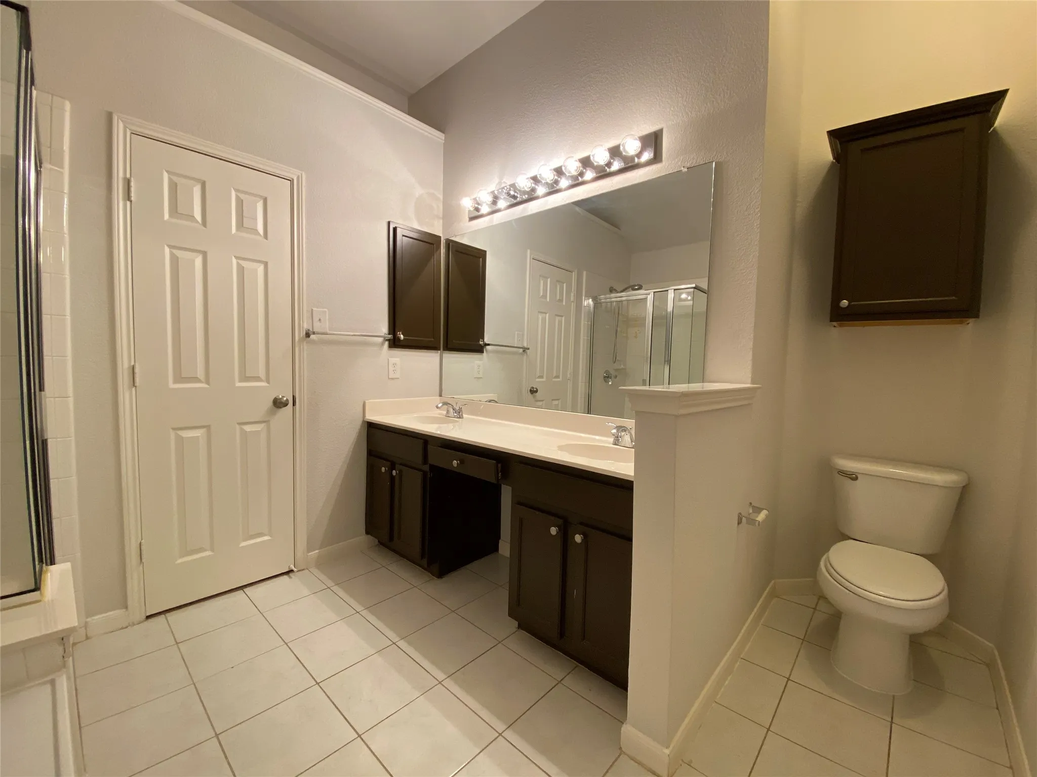 Bathroom with toilet, vanity, tile patterned floors, and an enclosed shower