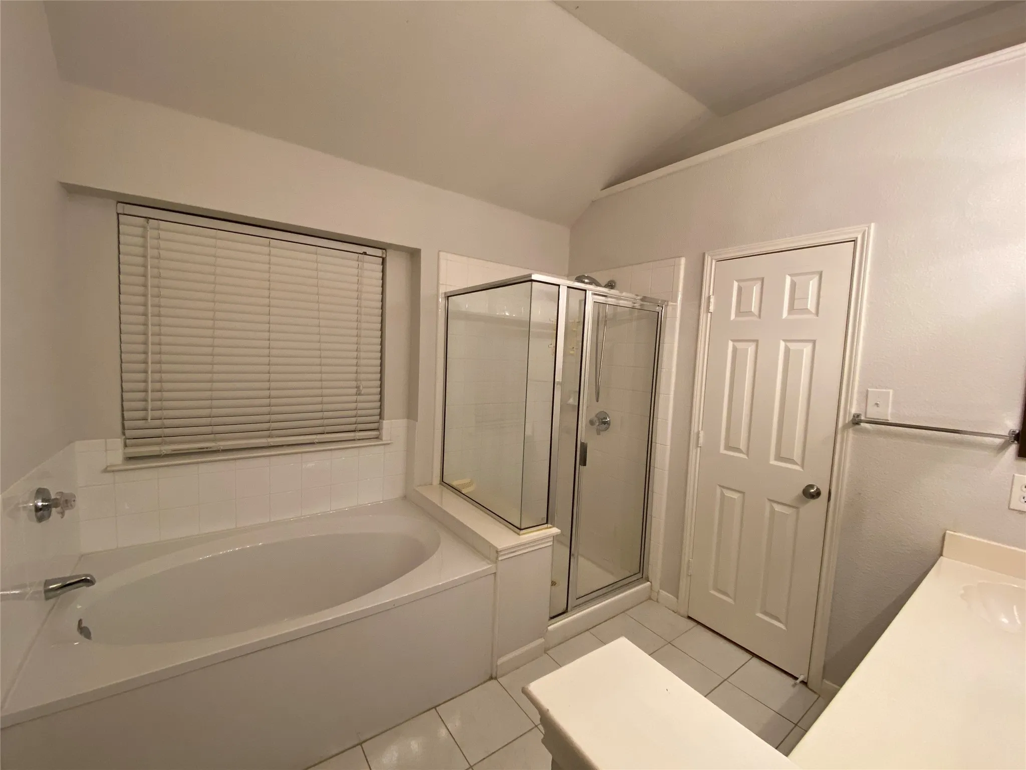 Bathroom with tile patterned floors, separate shower and tub, vanity, and lofted ceiling