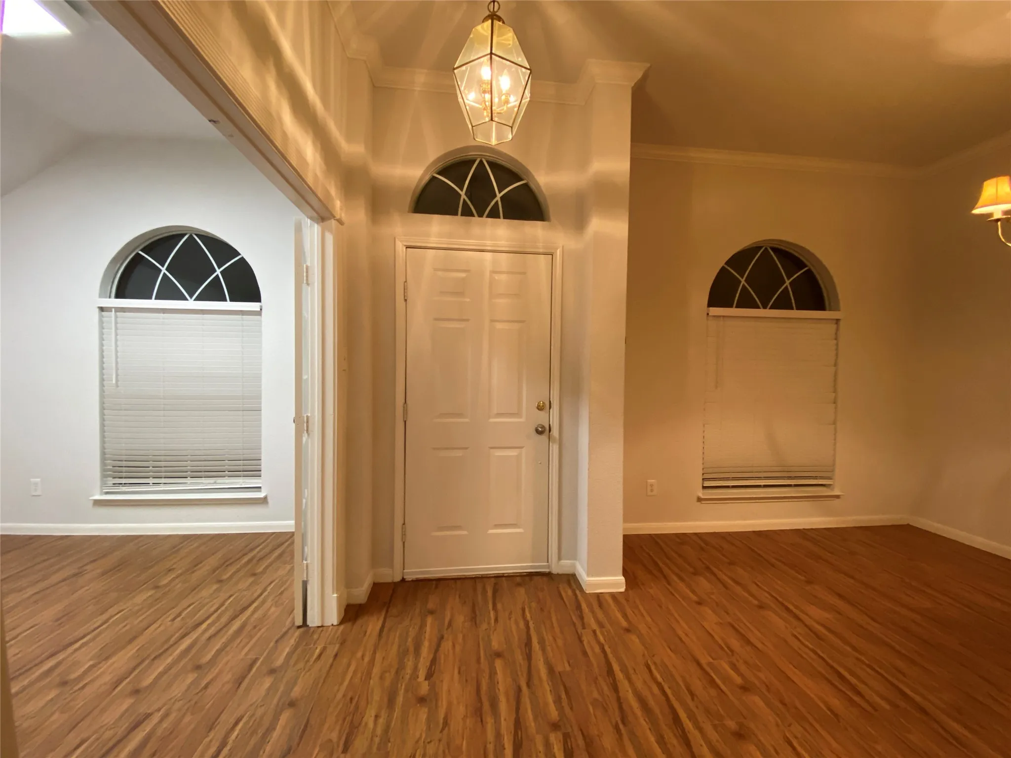 Entrance foyer featuring hardwood / wood-style flooring, a notable chandelier, crown molding, and vaulted ceiling