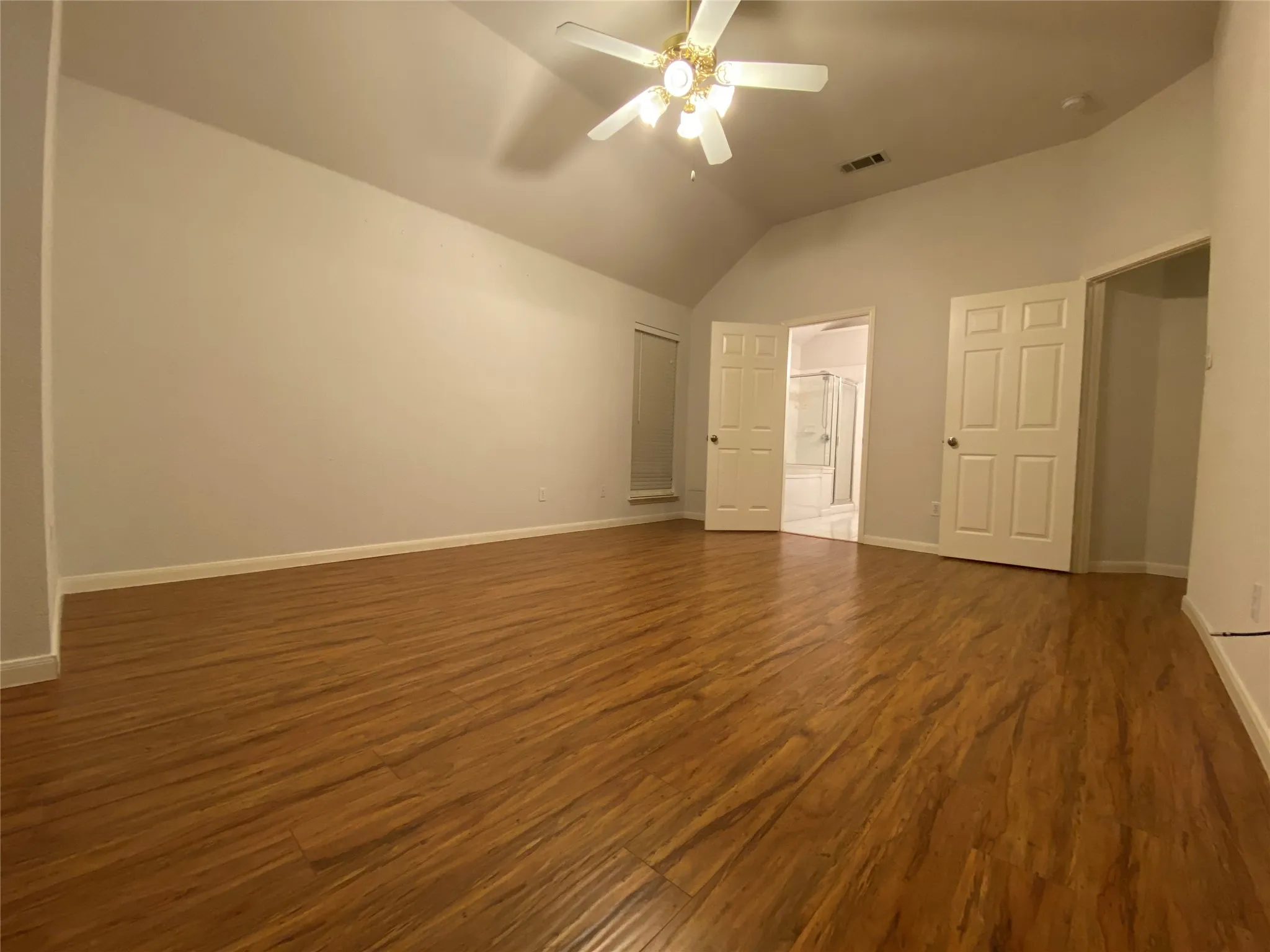 Unfurnished bedroom with dark hardwood / wood-style flooring, high vaulted ceiling, and ceiling fan