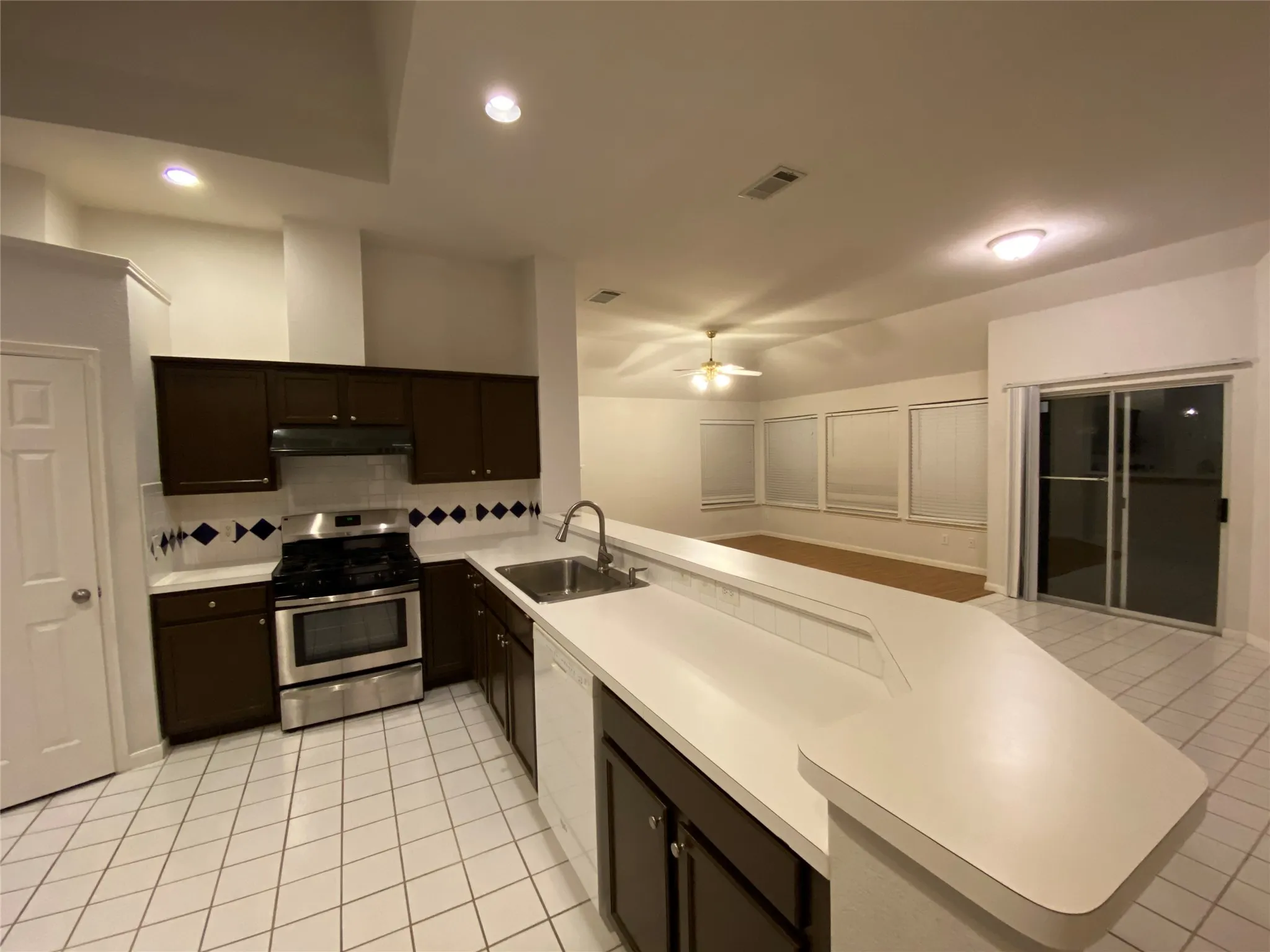 Kitchen with sink, gas range, light tile patterned floors, tasteful backsplash, and kitchen peninsula