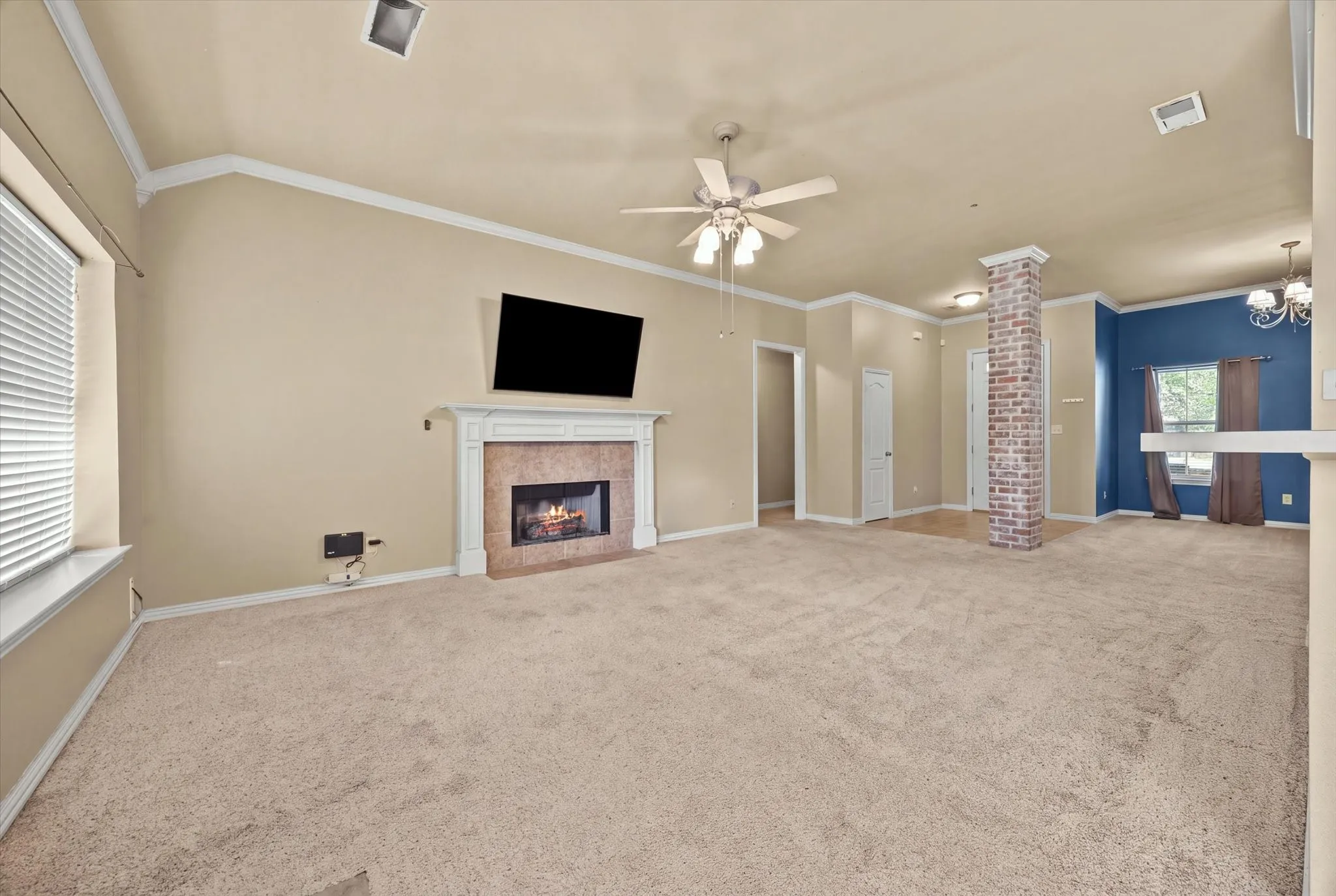 Vaulted ceiling, ceiling fan, fireplace with mantel, brick-clad column, and window with blinds