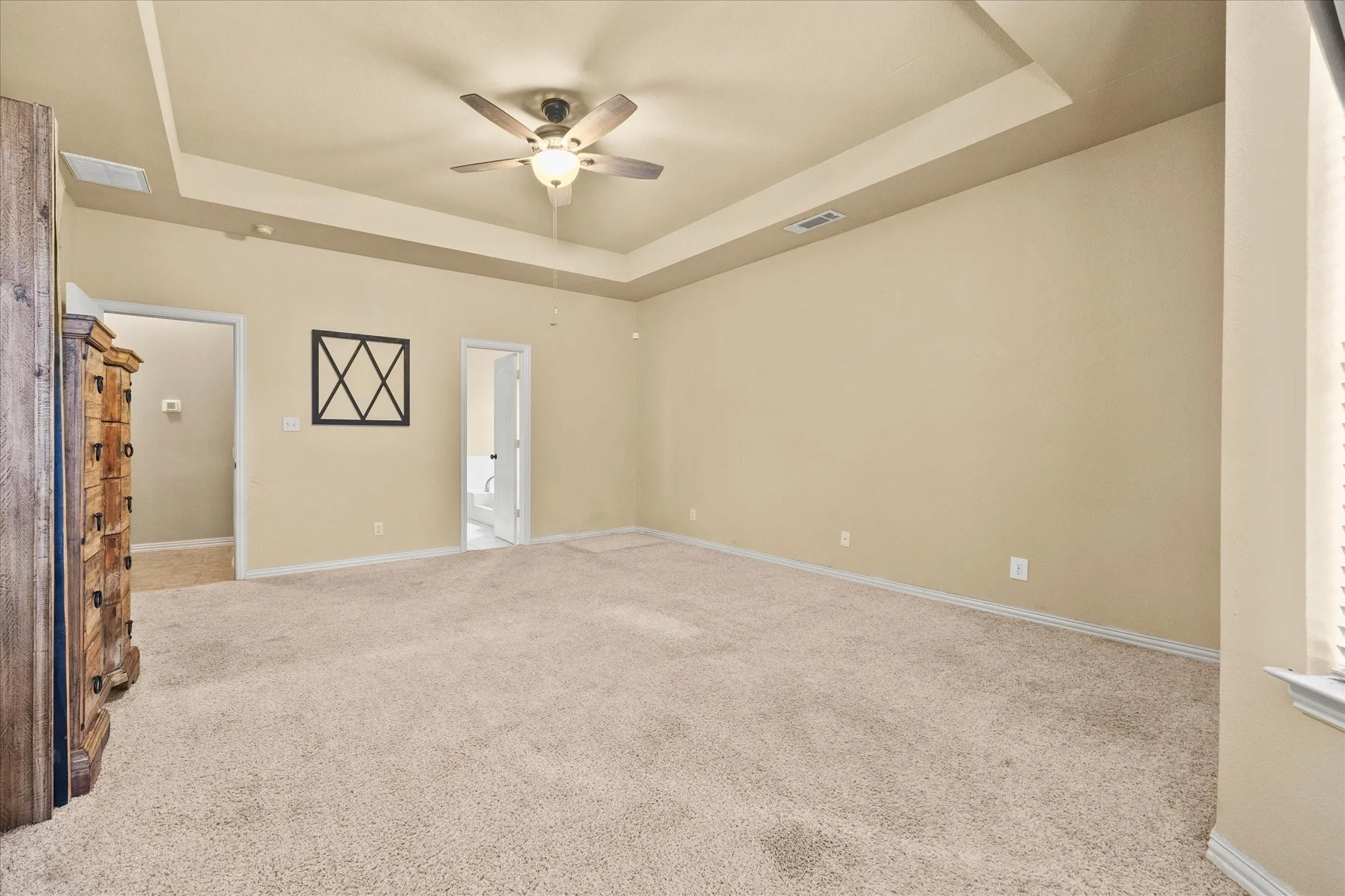 Recessed ceiling with an integrated ceiling fan, light neutral-toned walls, and carpet flooring