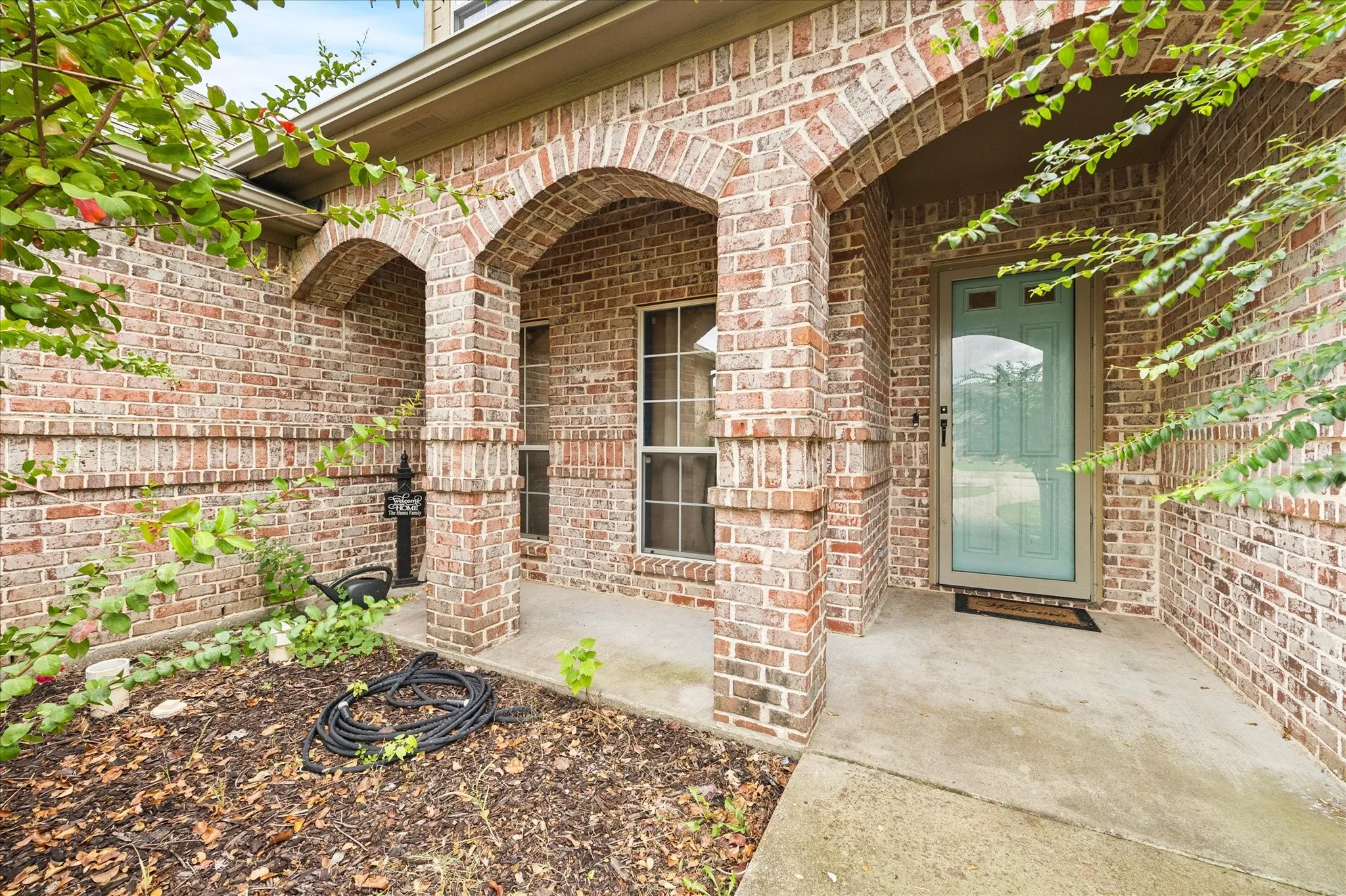 Brick exterior with arched entryways, covered porch, and light blue door