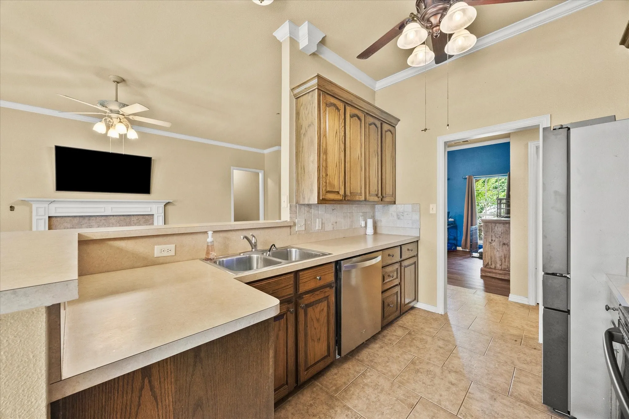 Kitchen featuring wood cabinetry, stainless steel dishwasher, dual basin sink, and tile flooring