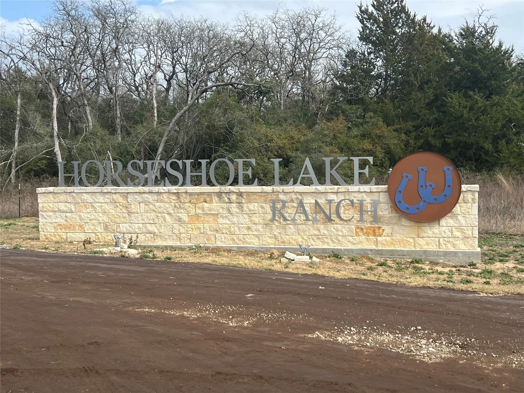 Stone block entrance monument featuring dimensional lettering and a circular brand emblem