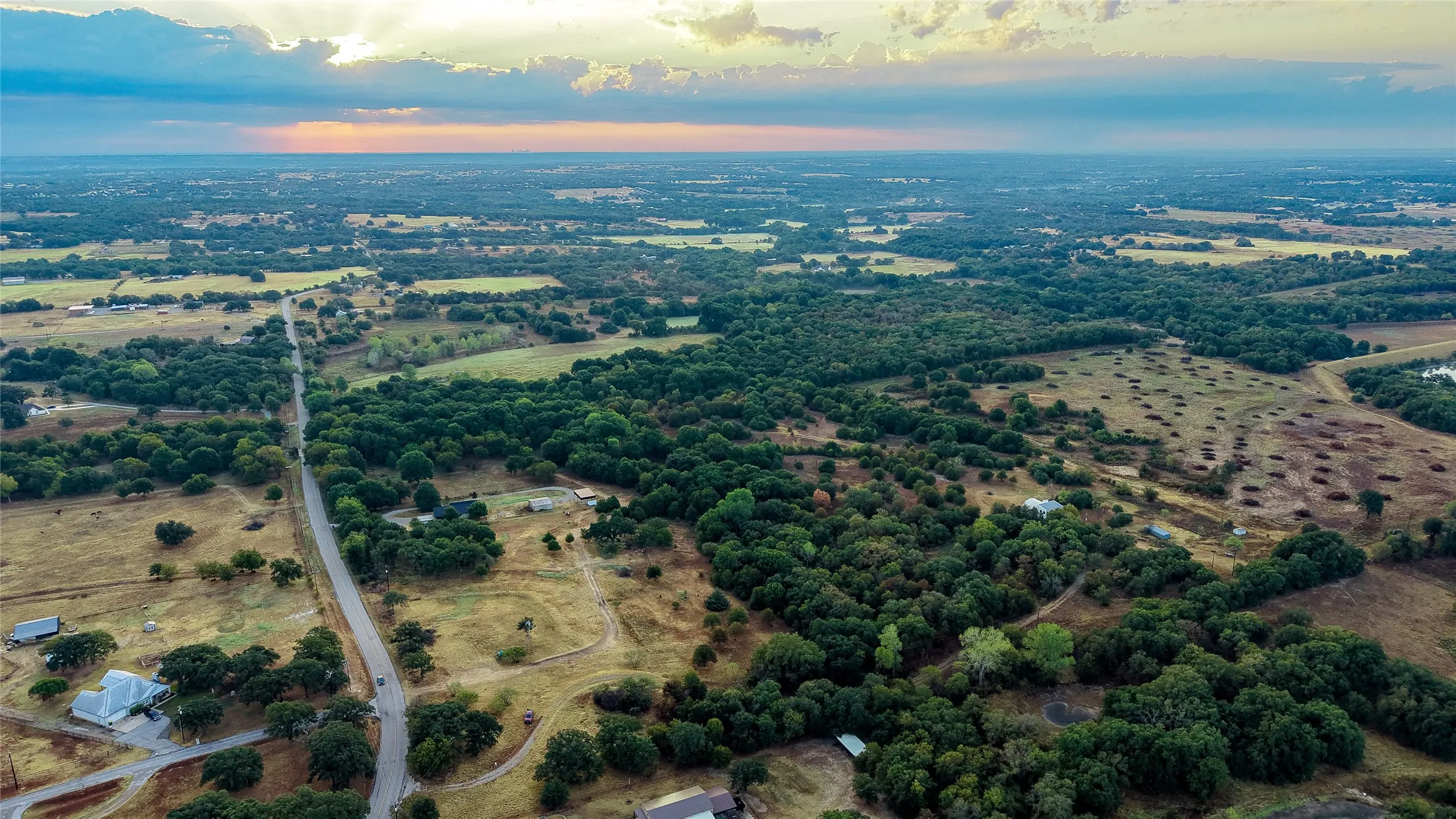 Expansive rural landscape with mature trees and a paved road