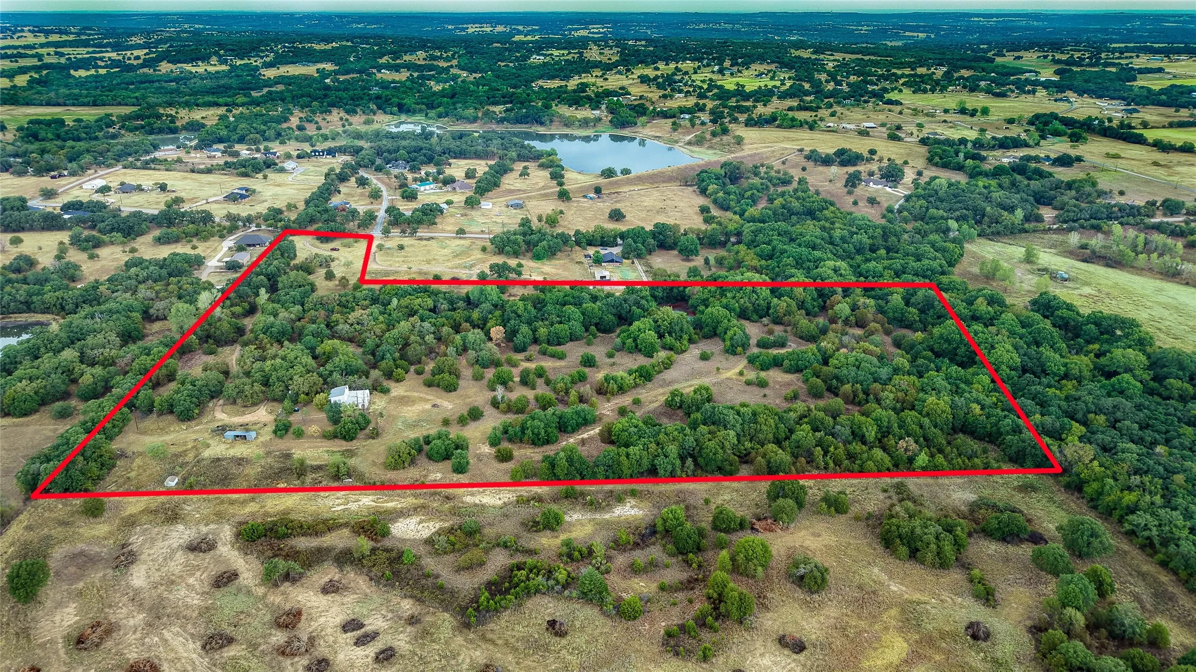 Expansive acreage featuring mature trees, open clearings, and perimeter delineation
