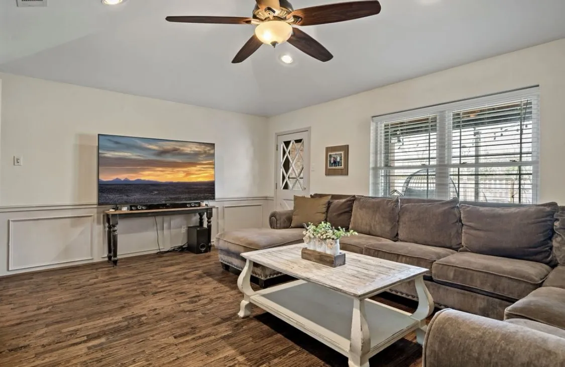 Living room featuring dark wood-style floors, recessed lighting, a wainscoted wall, and a ceiling fan