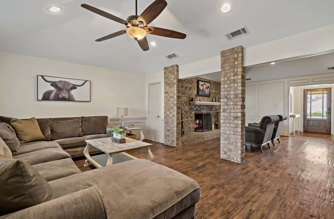 Living area featuring ornate columns, dark wood-style floors, visible vents, and a decorative wall