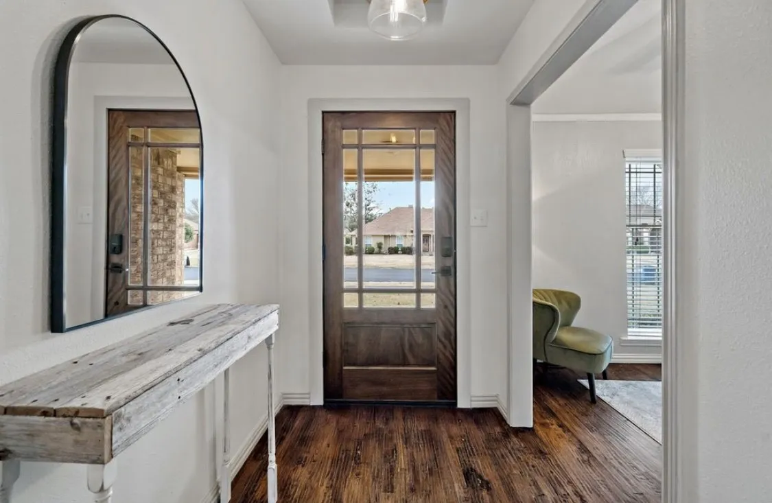 Entrance foyer with dark wood-style flooring and baseboards