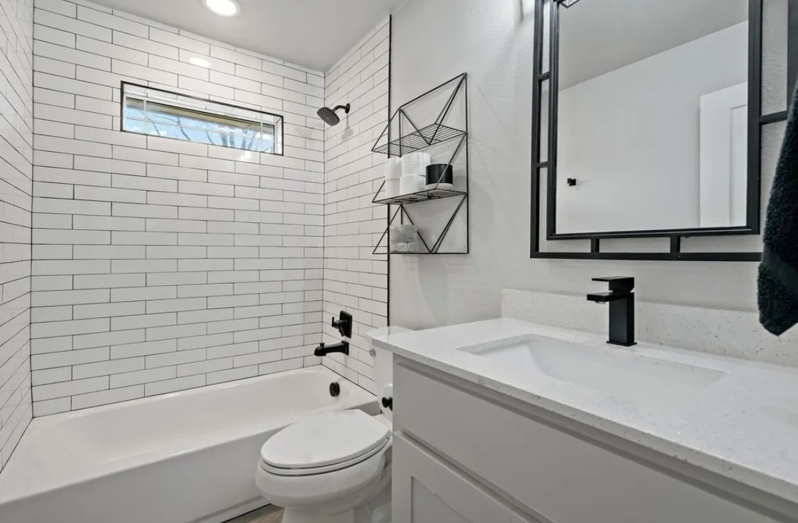 Bathroom with washtub / shower combination, vanity, and toilet