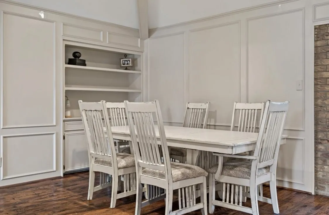 Dining space featuring a decorative wall and dark wood-type flooring