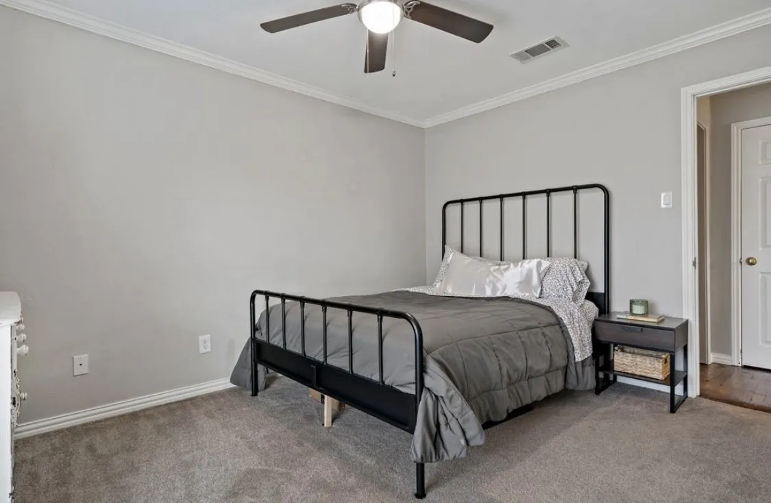 Bedroom with ornamental molding, visible vents, and carpet flooring