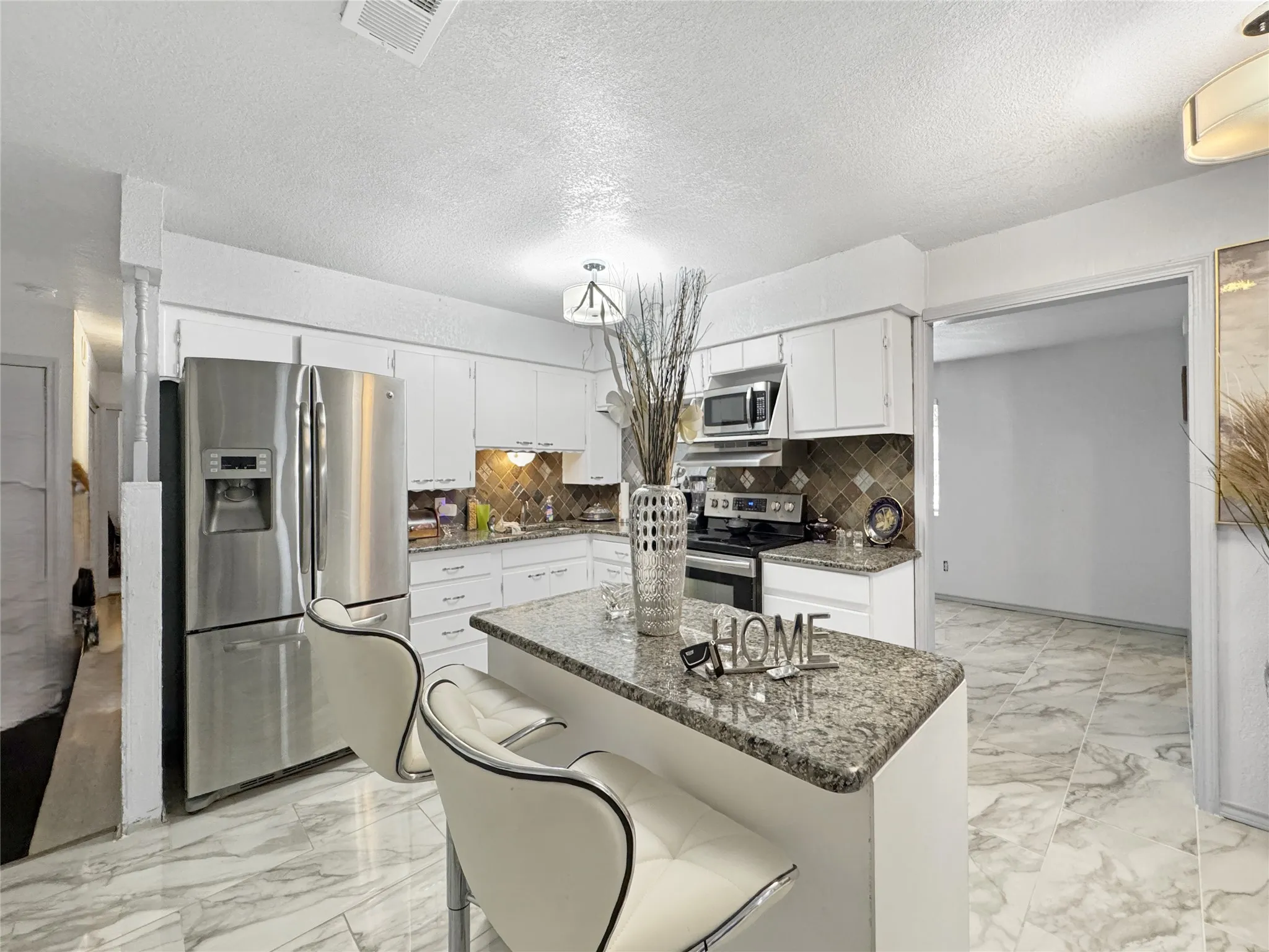 Kitchen featuring white cabinetry, stainless steel appliances, granite countertops, and a tiled backsplash