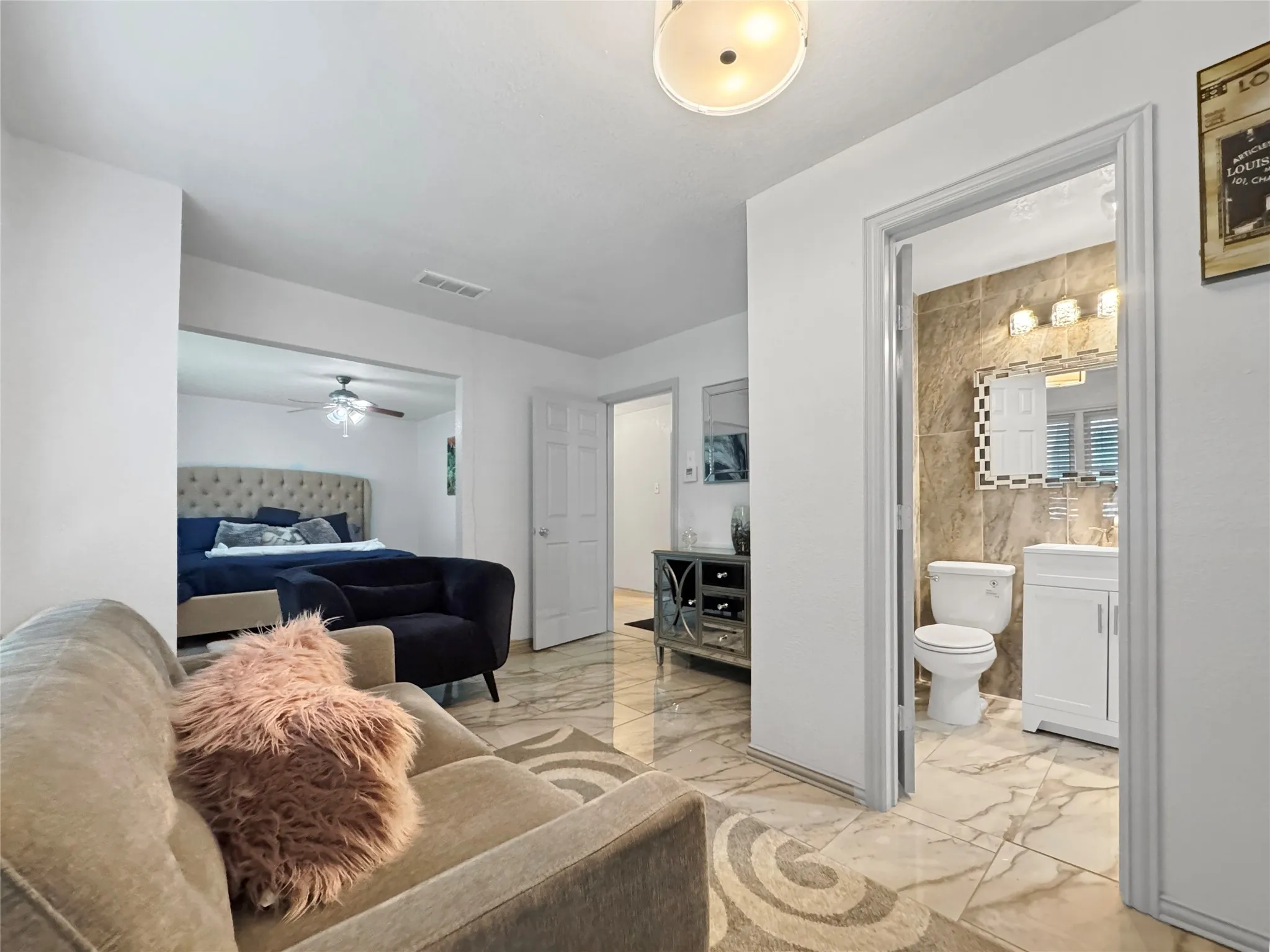 Marble-patterned tile flooring extends throughout, featuring a recessed bedroom area with a ceiling fan