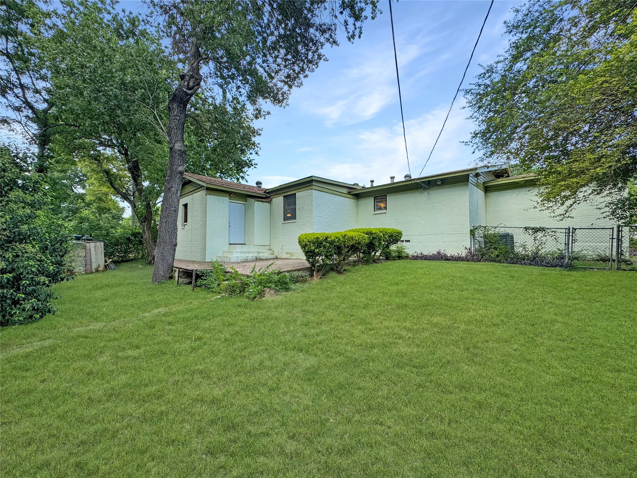 Expansive green lawn, mature trees, and a ground-level deck