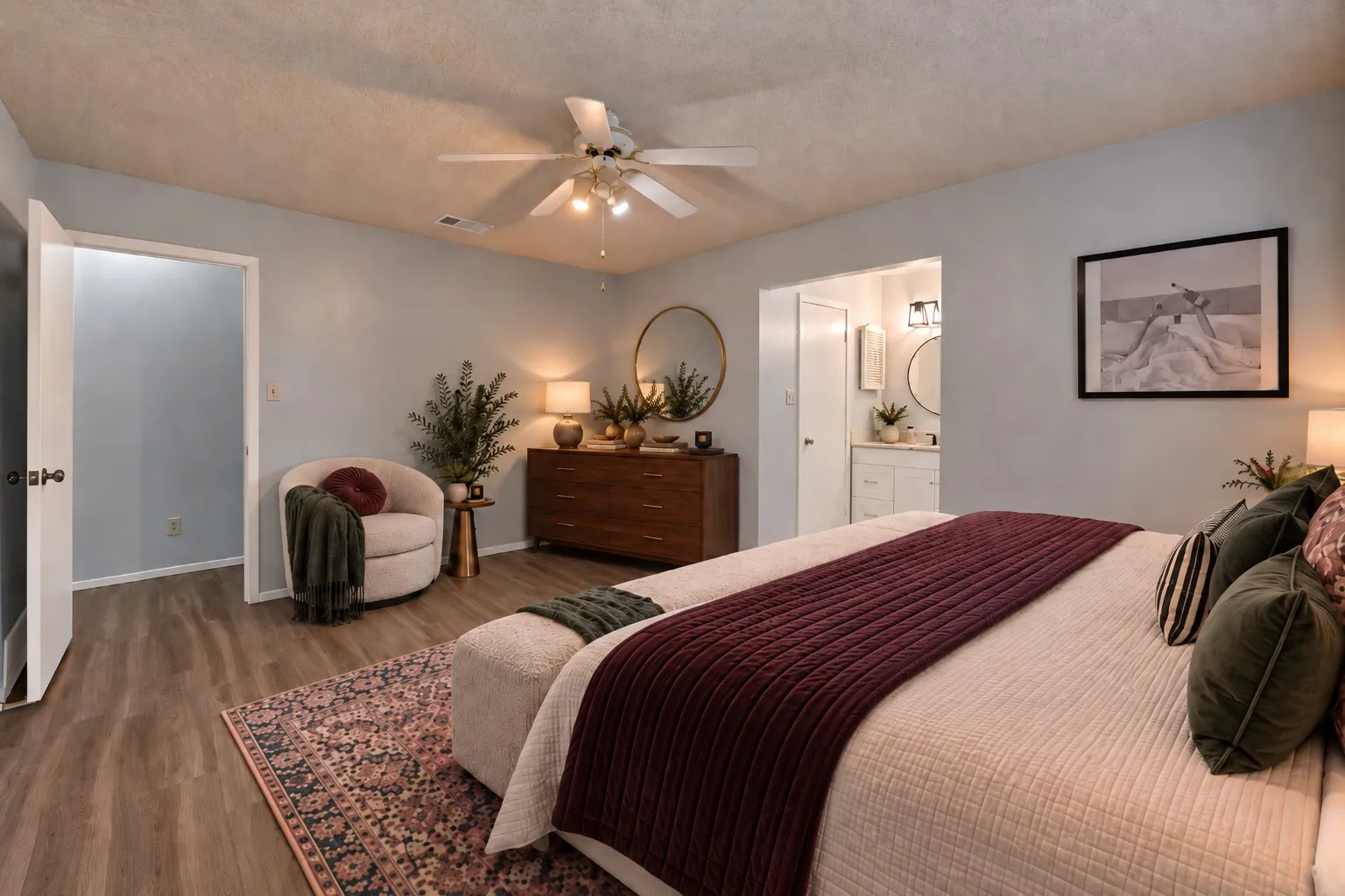 Primary bedroom: Window overlooking the covered back patio and ensuite bath with white vanity. Virtually staged.