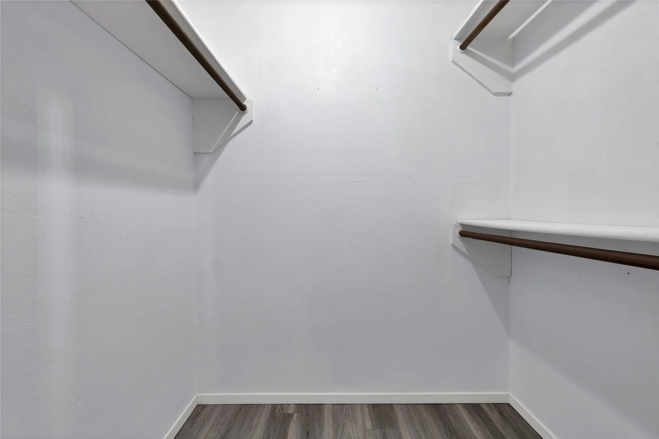 Walk-in closet: Walk-in closet with hanging rods and shelving on multiple walls.