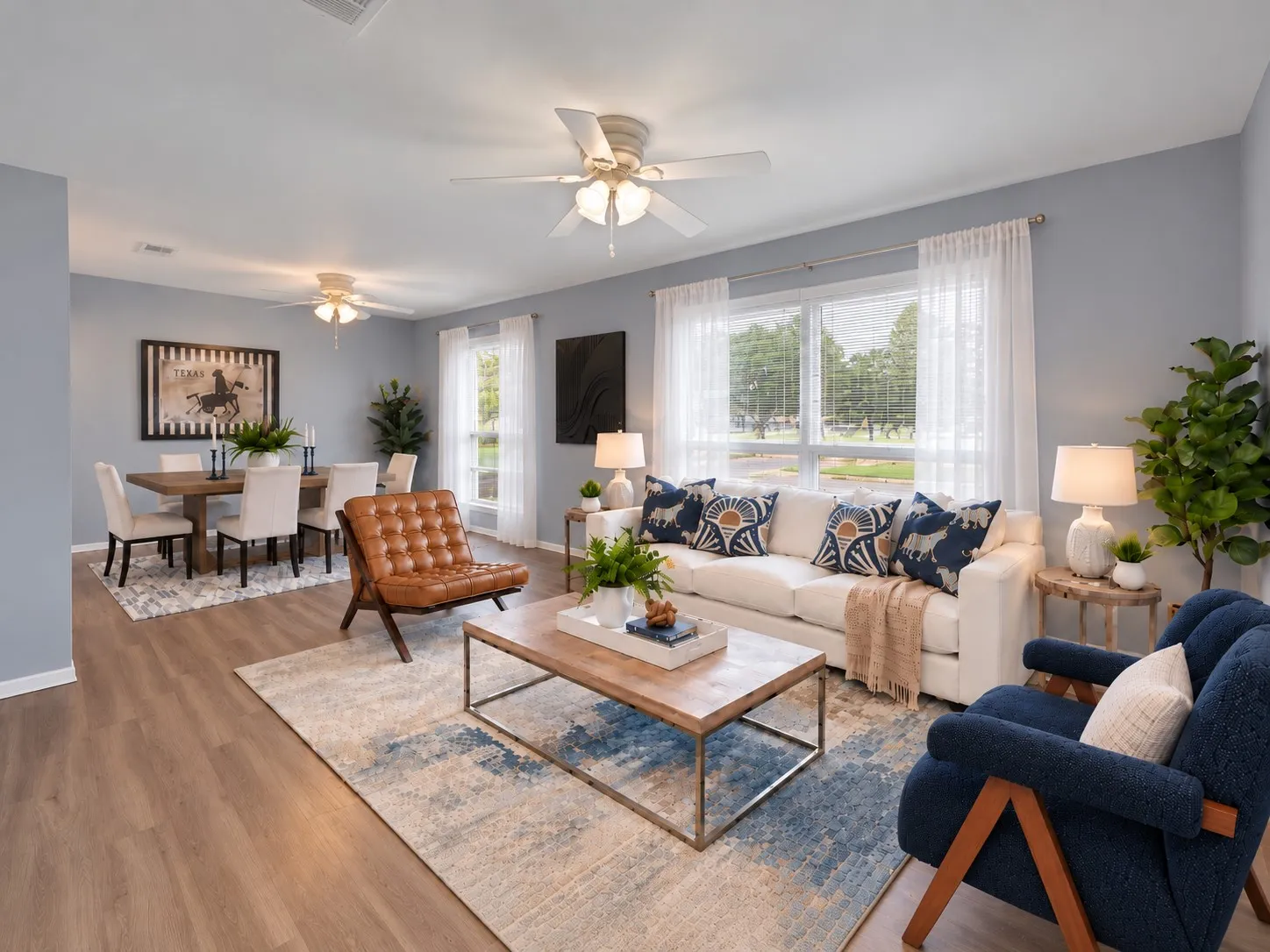 Front living room: Picture window overlooking the front yard, two ceiling fans, and open flow to the dining area. Virtually staged.