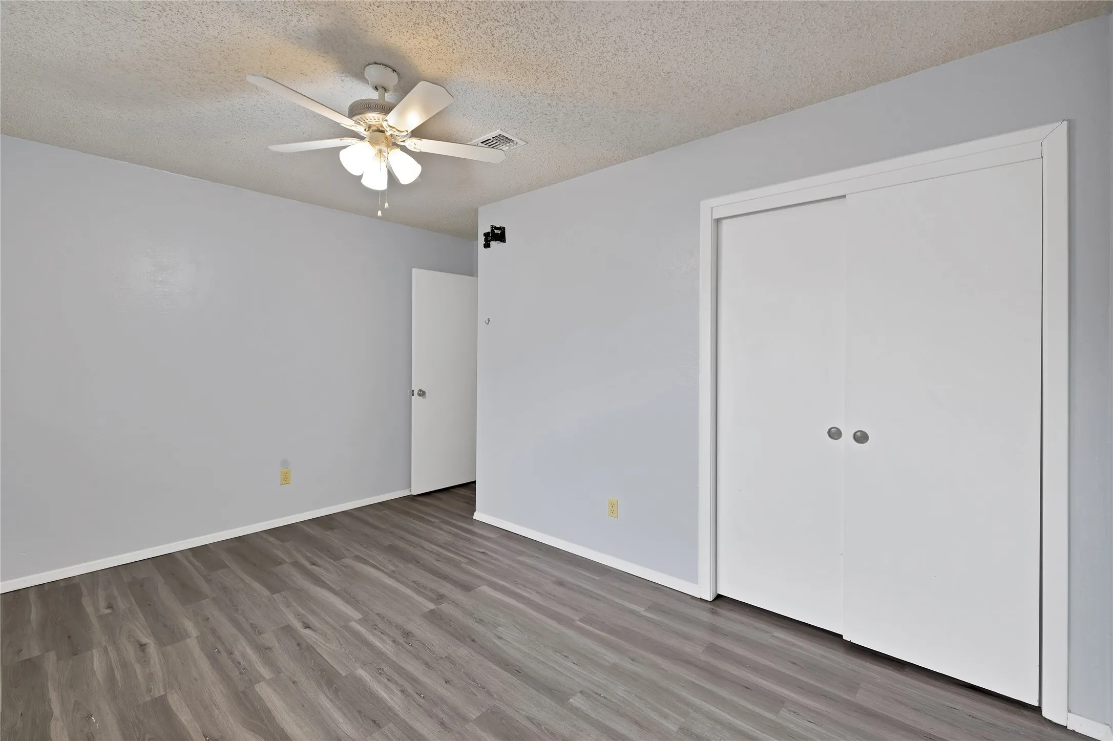 Bedroom with sliding door closet, ceiling fan, and wood-look plank flooring
