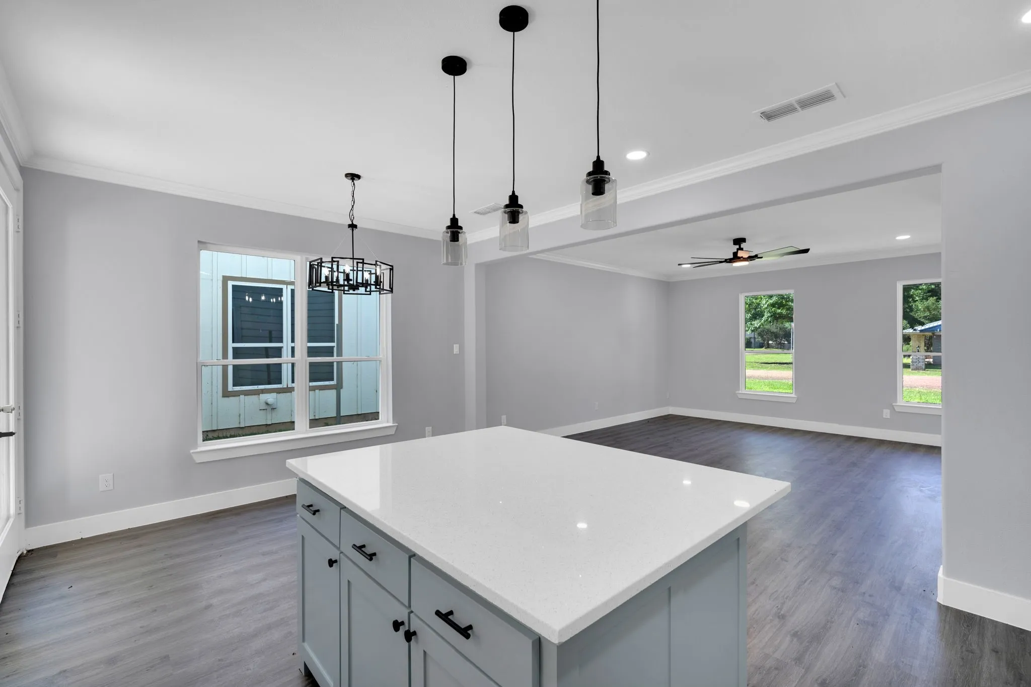 Kitchen island with a white countertop and light blue cabinetry, featuring pendant lighting and recessed illumination