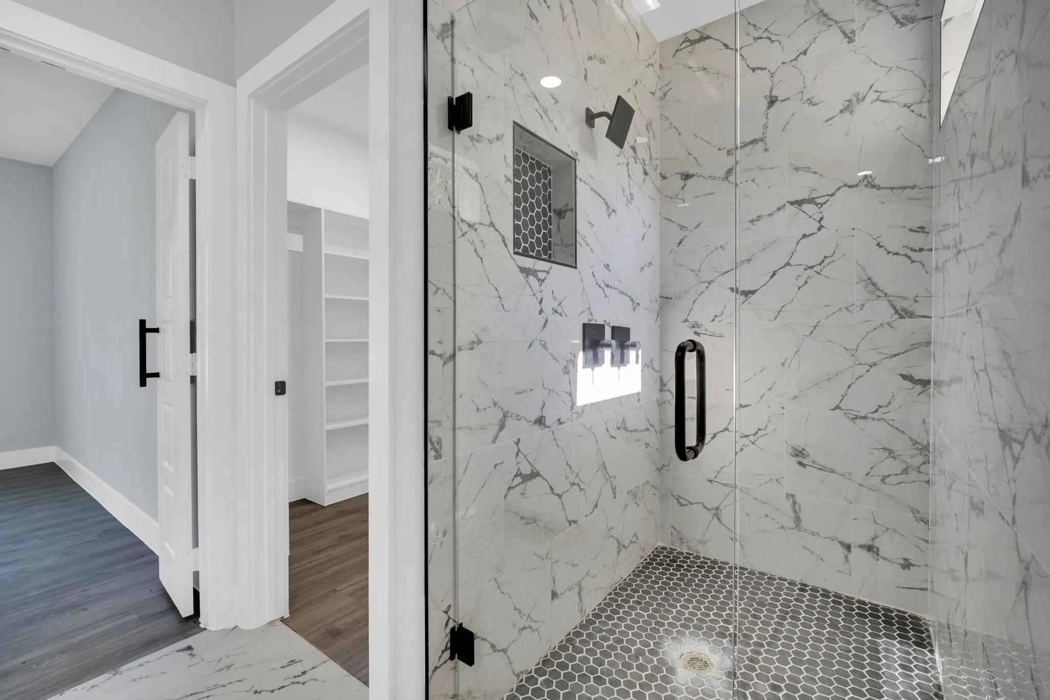 Walk-in shower featuring a glass enclosure, a rain showerhead, a tile niche, and hexagonal tile flooring