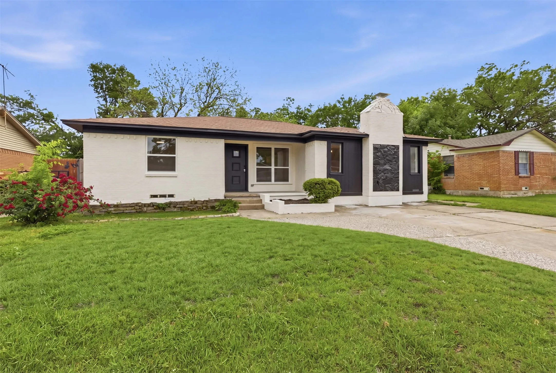 White painted brick exterior with dark trim and a brown shingle roof