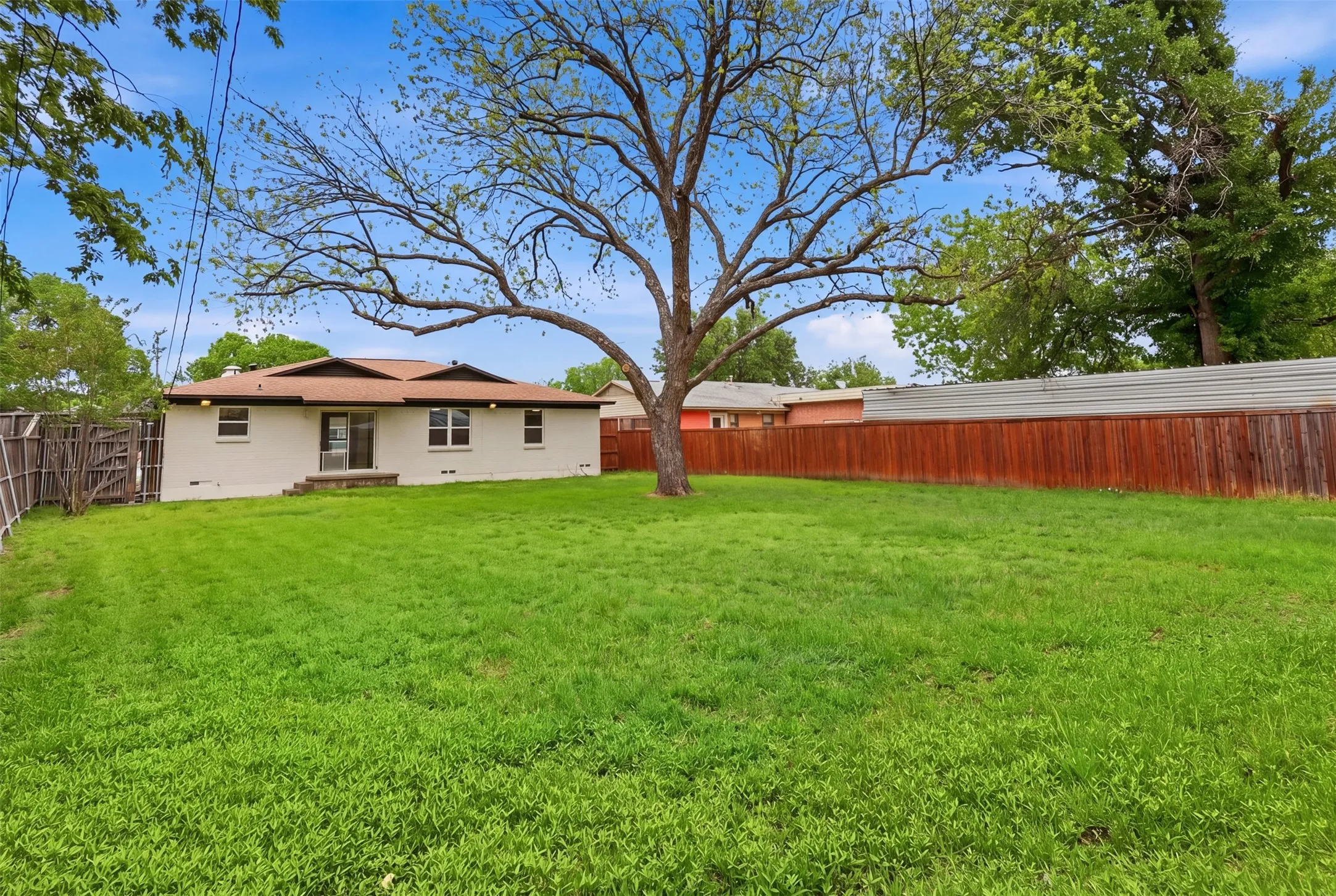 Expansive lawn with mature trees and a privacy fence