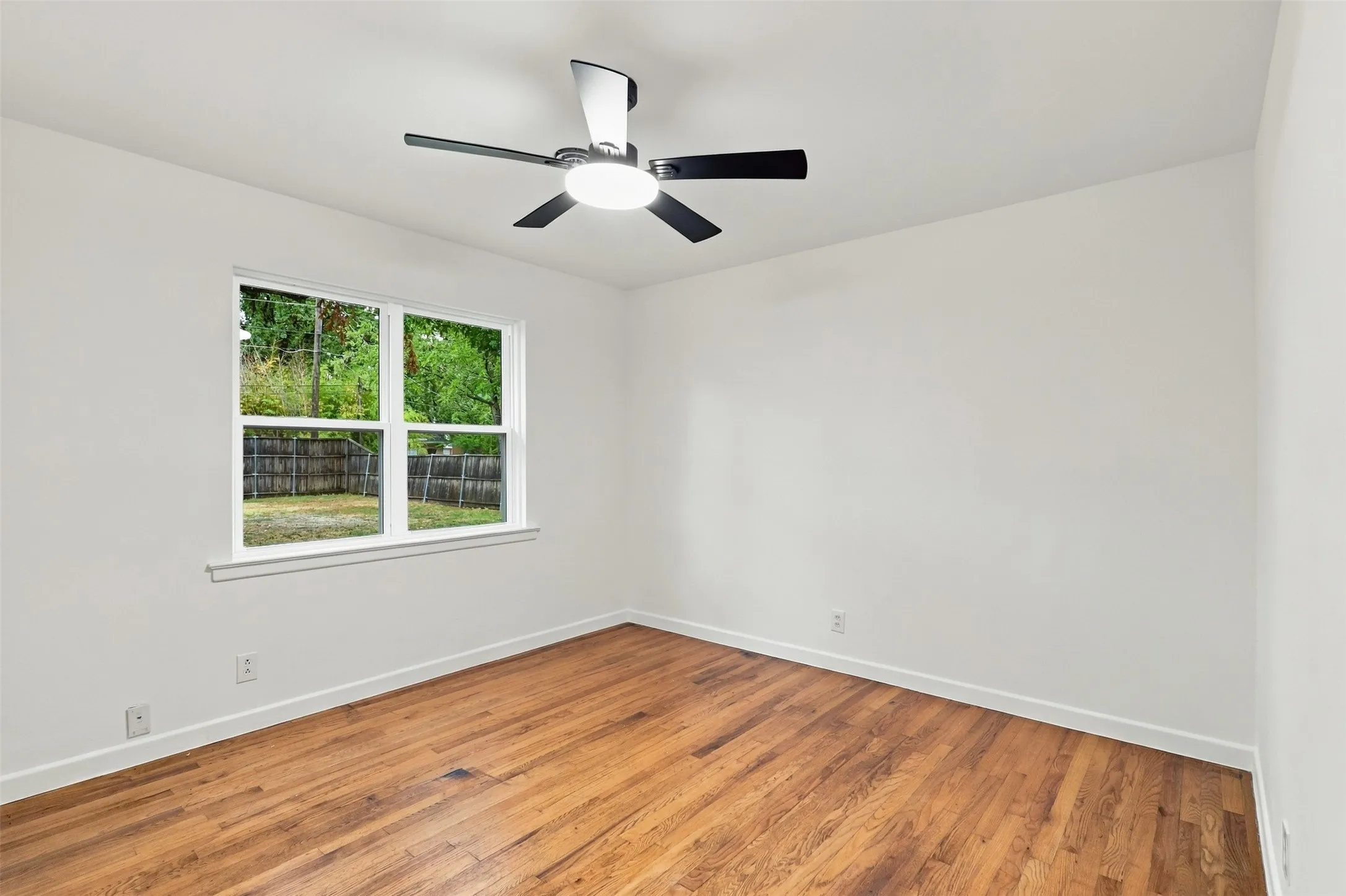 Hardwood flooring, white painted walls, ceiling fan with integrated lighting, a double-hung window, and white trim