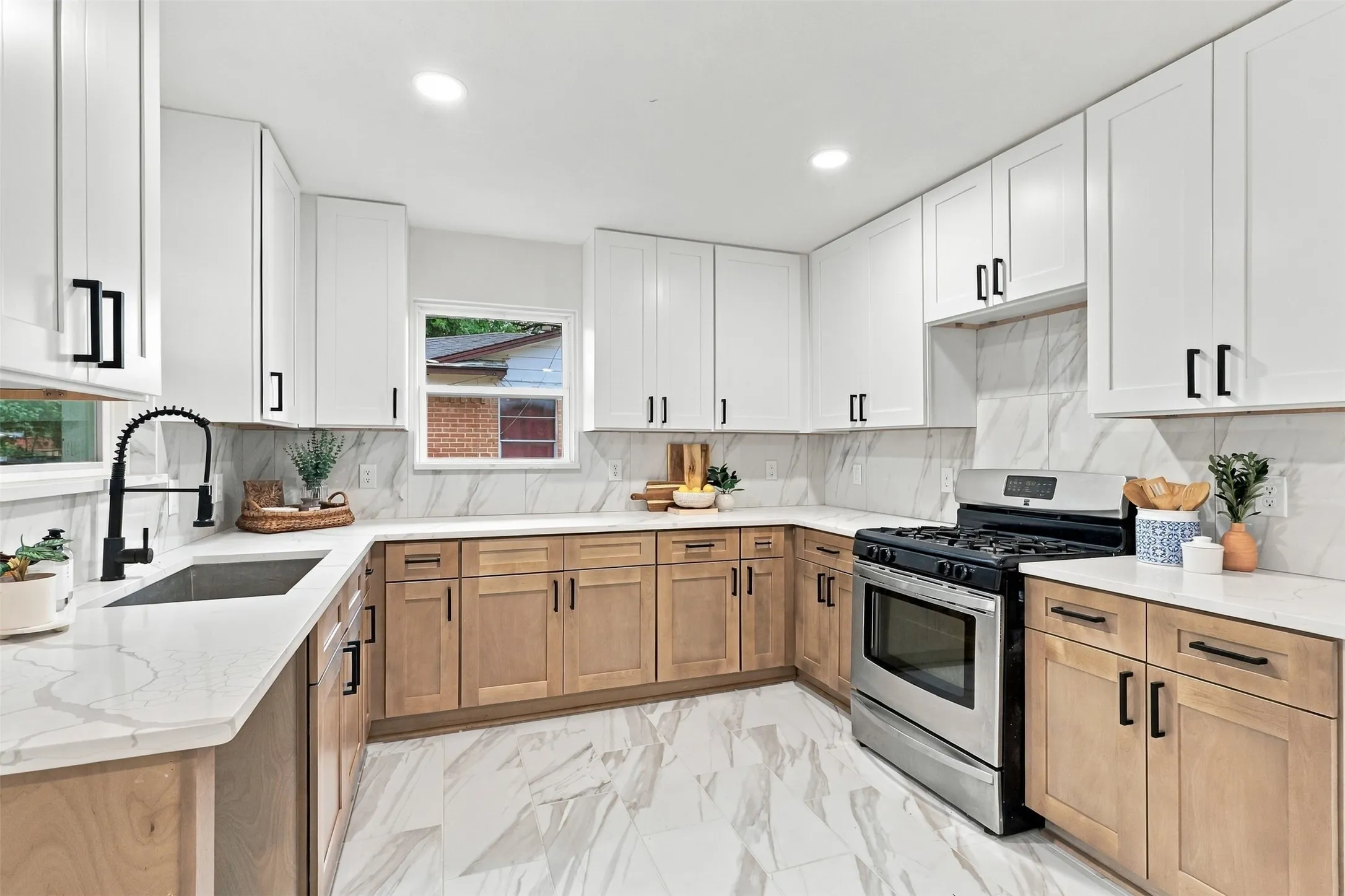 Contemporary kitchen featuring a stainless steel range, white upper cabinetry, natural wood-finish lower cabinetry, white countertops, and a white tile backsplash